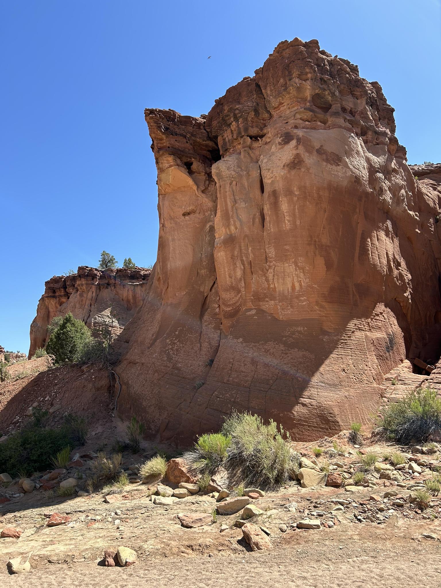 Tall, weathered red rock formation with a clear blue sky overhead.