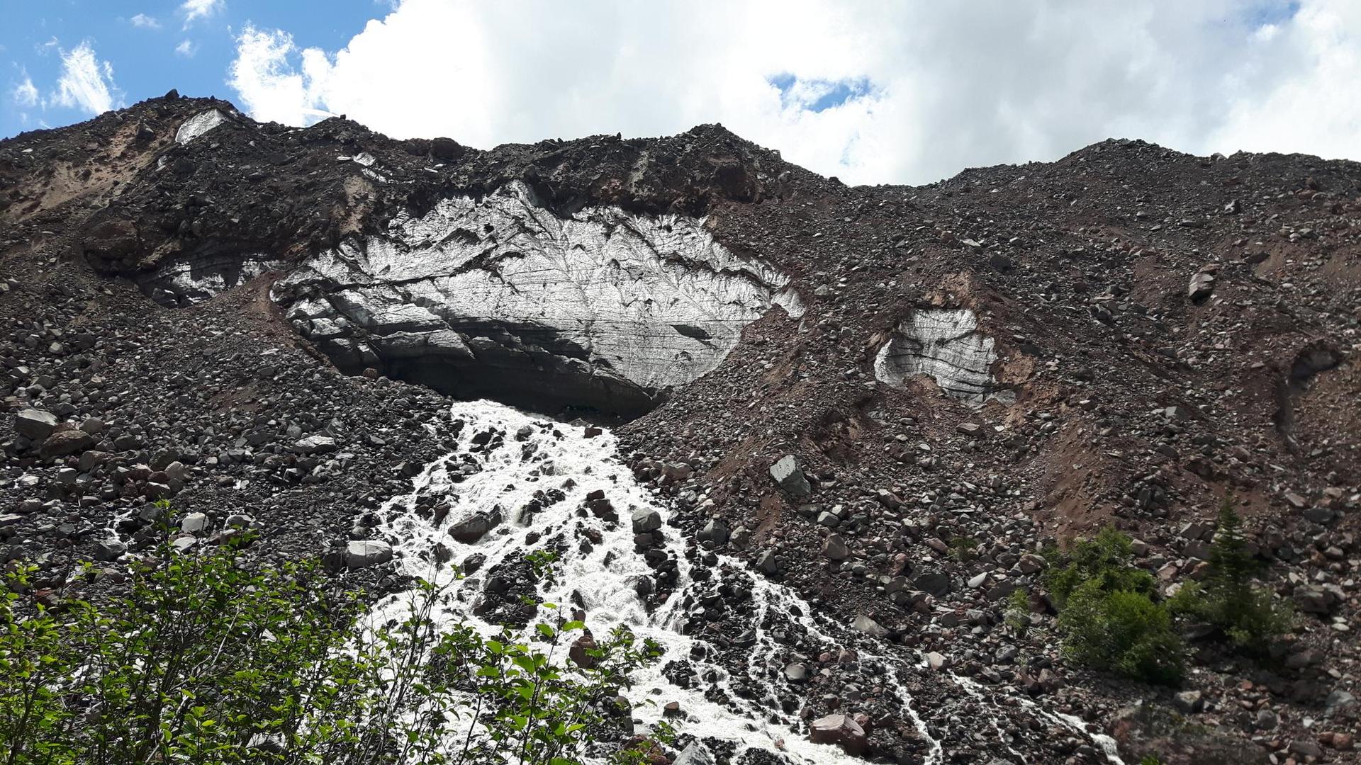 Water cascading from a melting glacier in a rocky mountain slope.