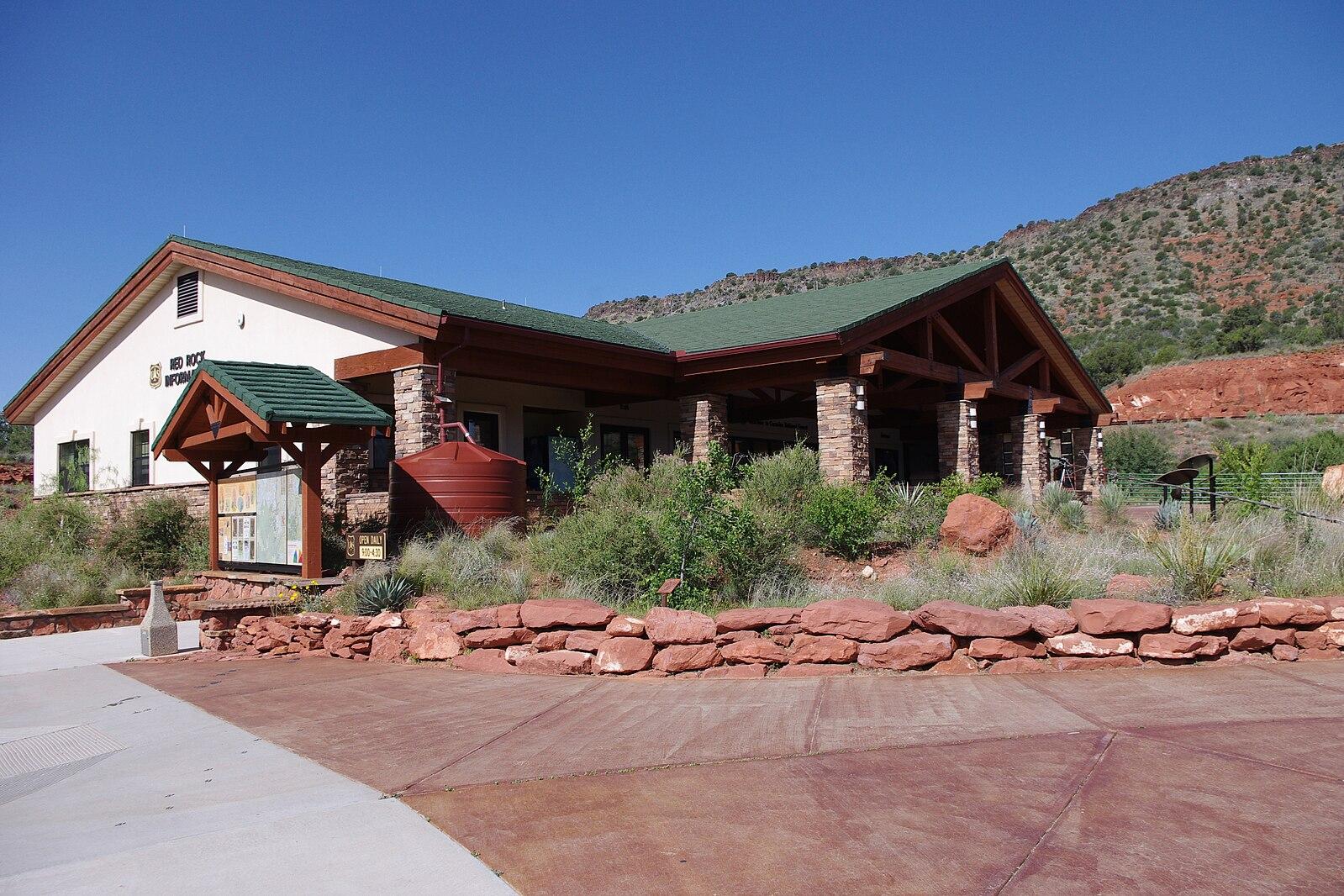 A building with a green roof and stone facade against a rocky hill.