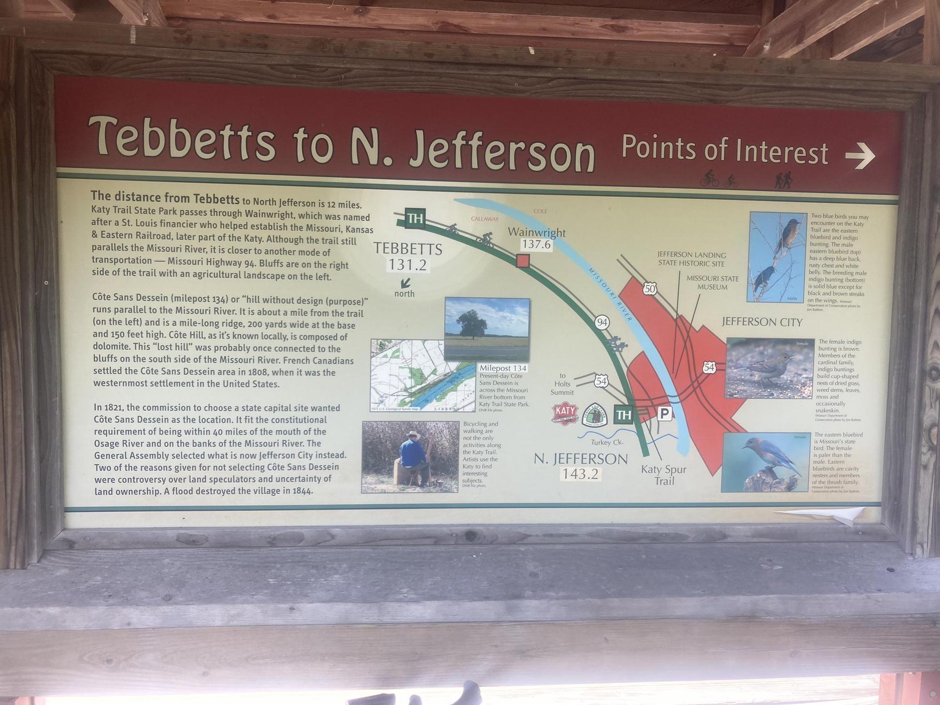 Informational sign with maps, text, and images about points of interest.