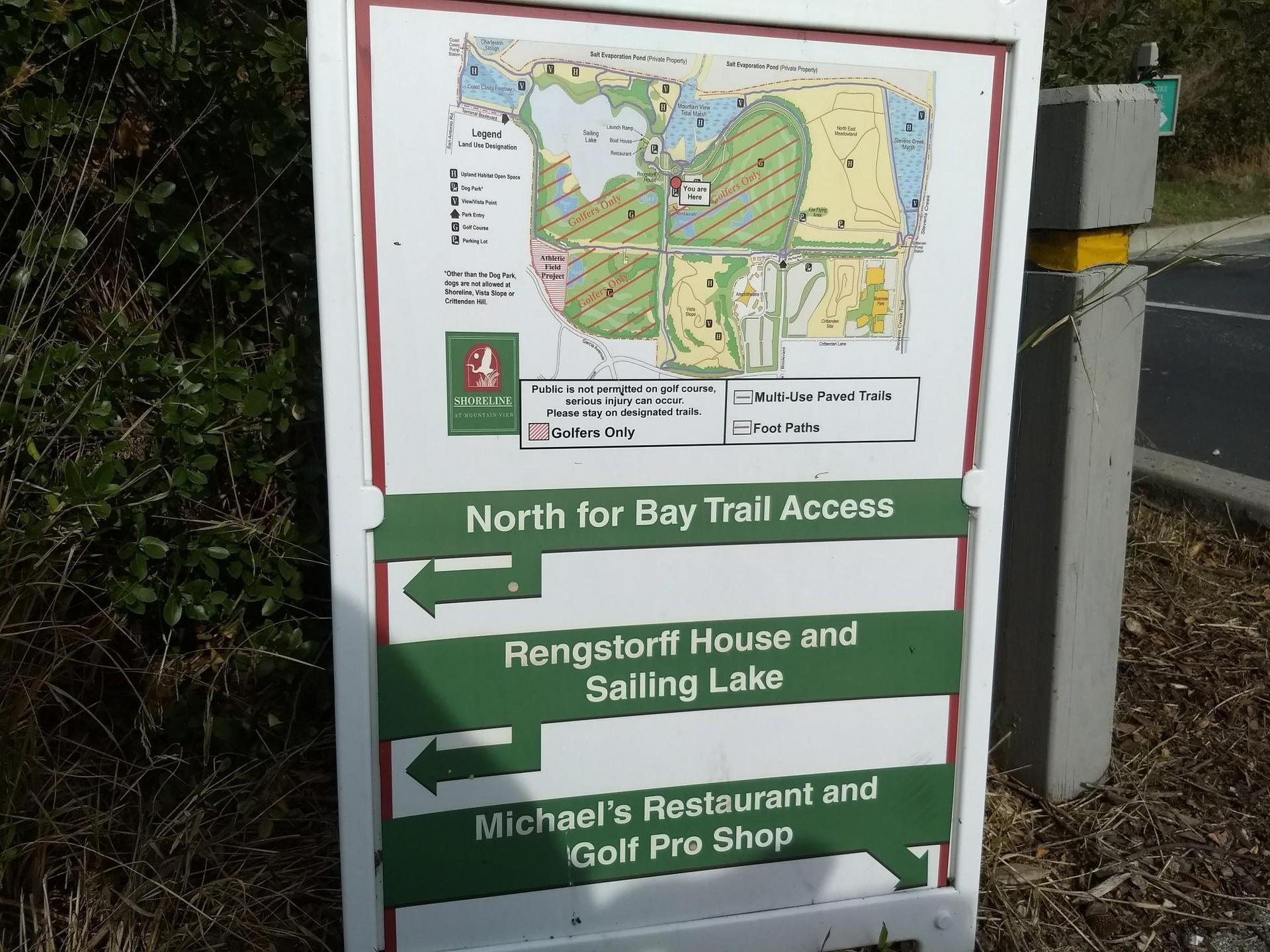 Close-up of a white sign board with a map and directional arrows.