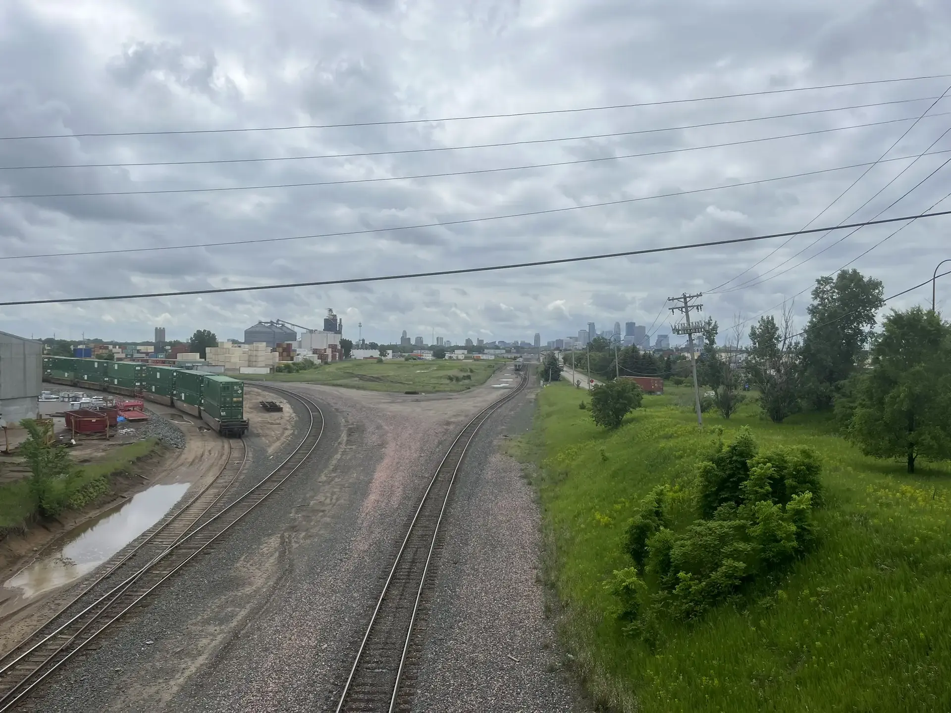 Train tracks diverge in an industrial area under an overcast sky.