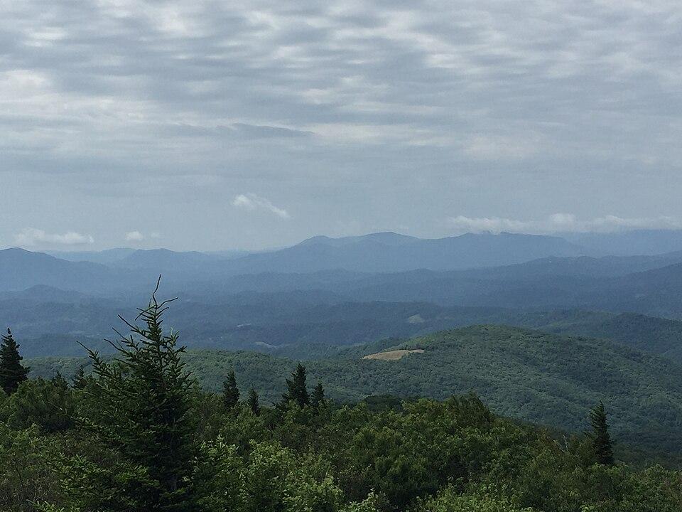 Distant blue mountains and green forested hills under an overcast sky.