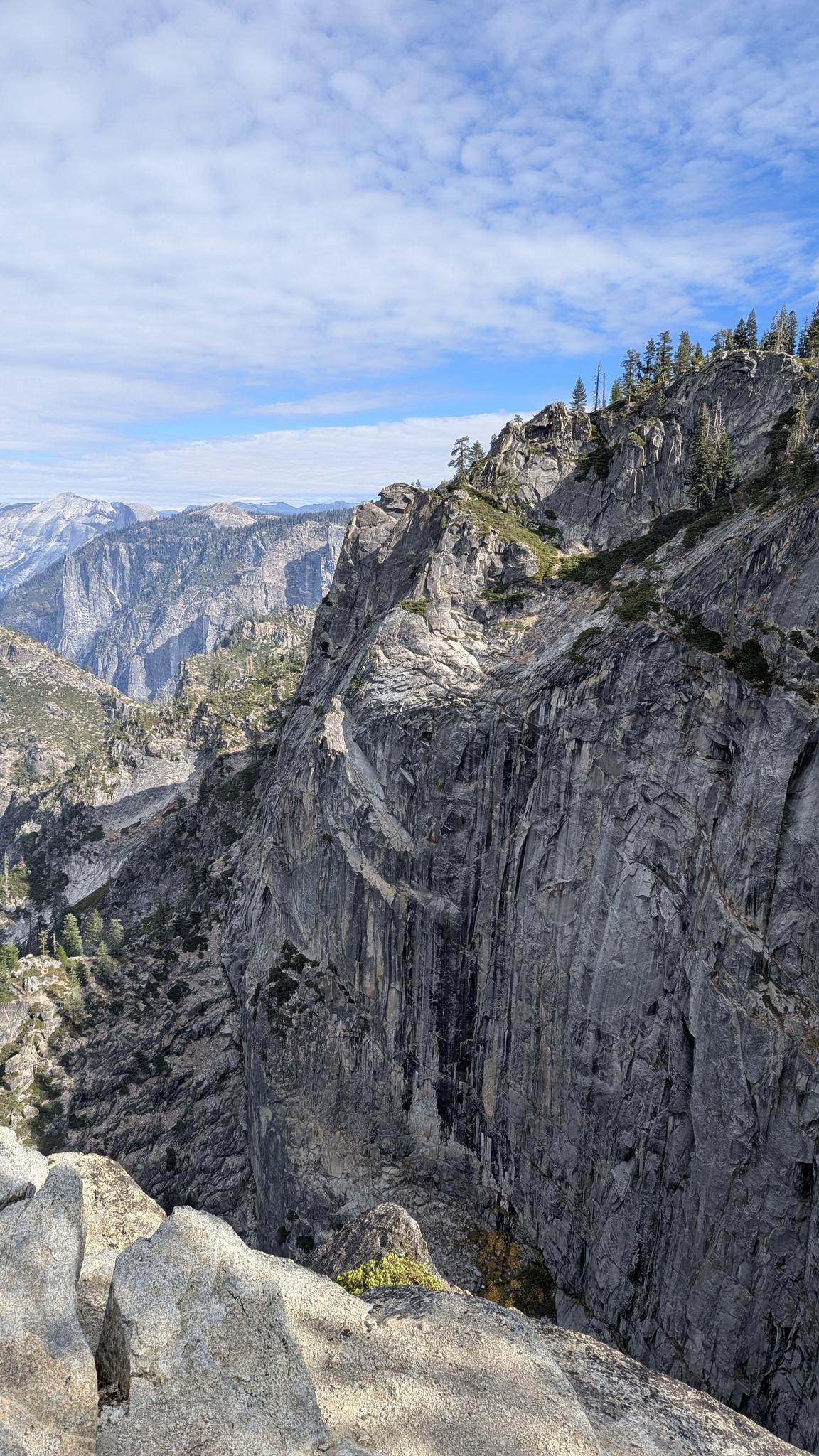 Close-up of a massive, textured granite cliff face with distant mountains.