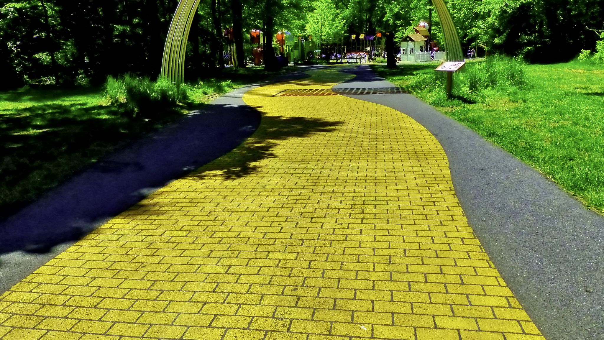 Bright yellow brick path curves through a sunny green park with trees. - WB&A and East Coast Greenway Loop from Odenton