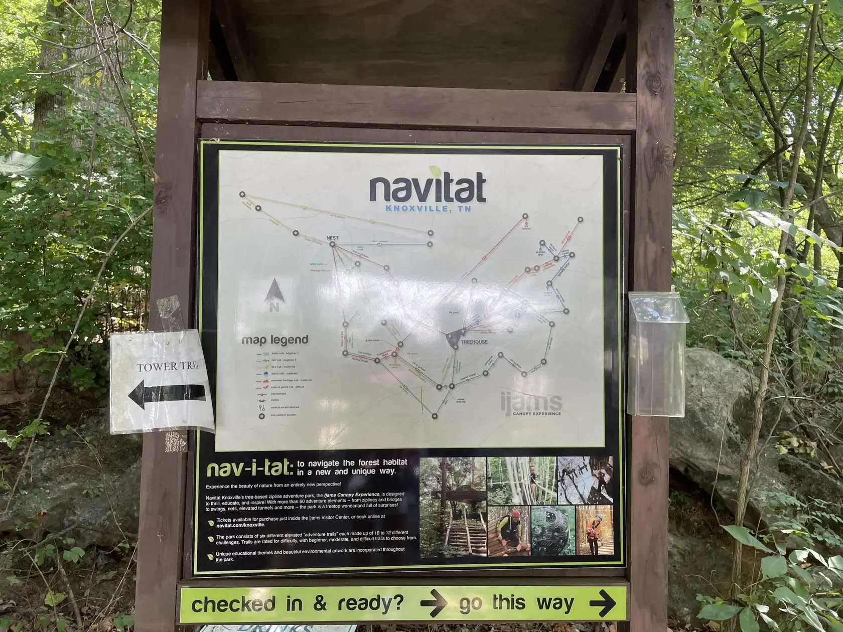 Outdoor information board with a map and activity details in a green forest.