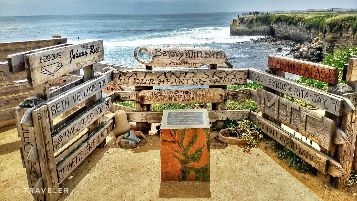Wooden memorial fence with plaques overlooking a dramatic ocean coastline.