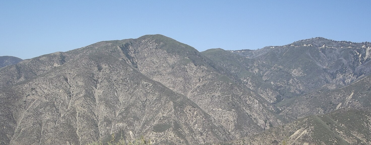 Expansive view of rugged, arid mountains under a clear blue sky. - Daley Canyon Road Trail