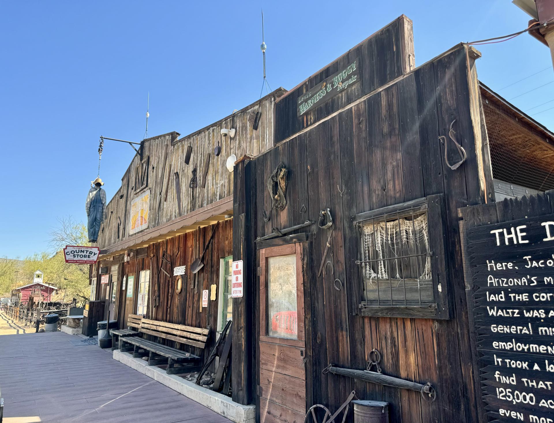 Rustic wooden buildings with western decor under a bright blue sky.