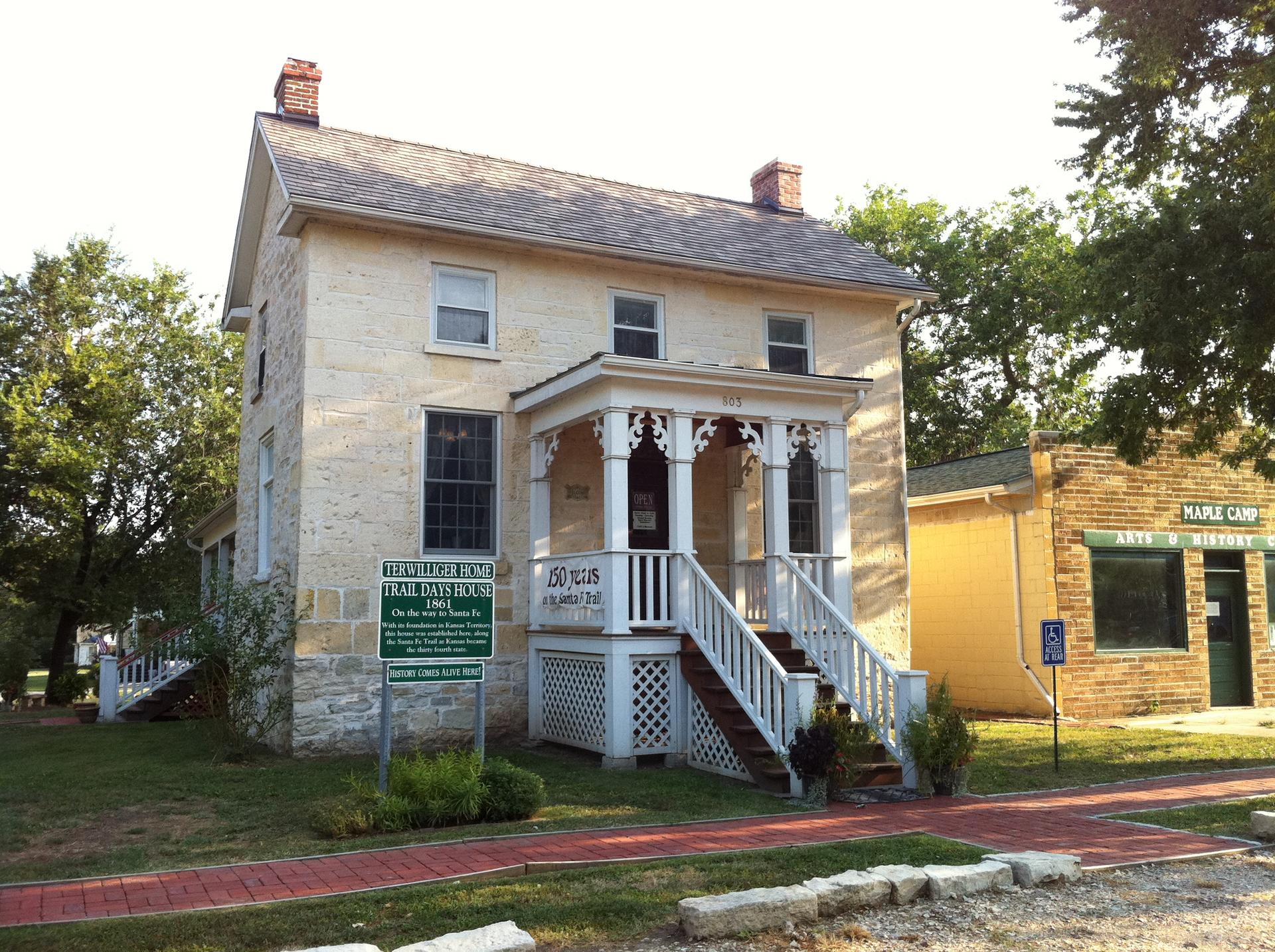 Historic stone building with a white porch and steps on a sunny day.
