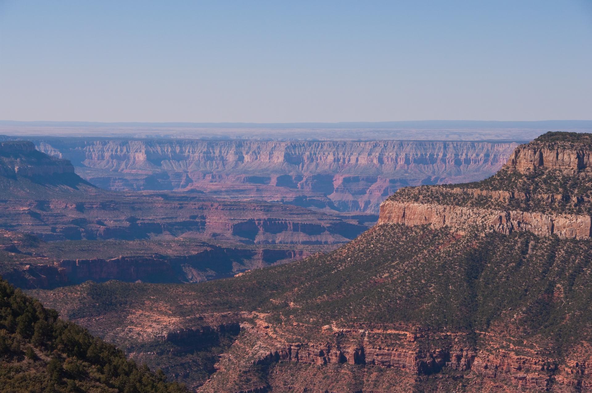 Layered rock formations and distant mesas under a clear blue sky.