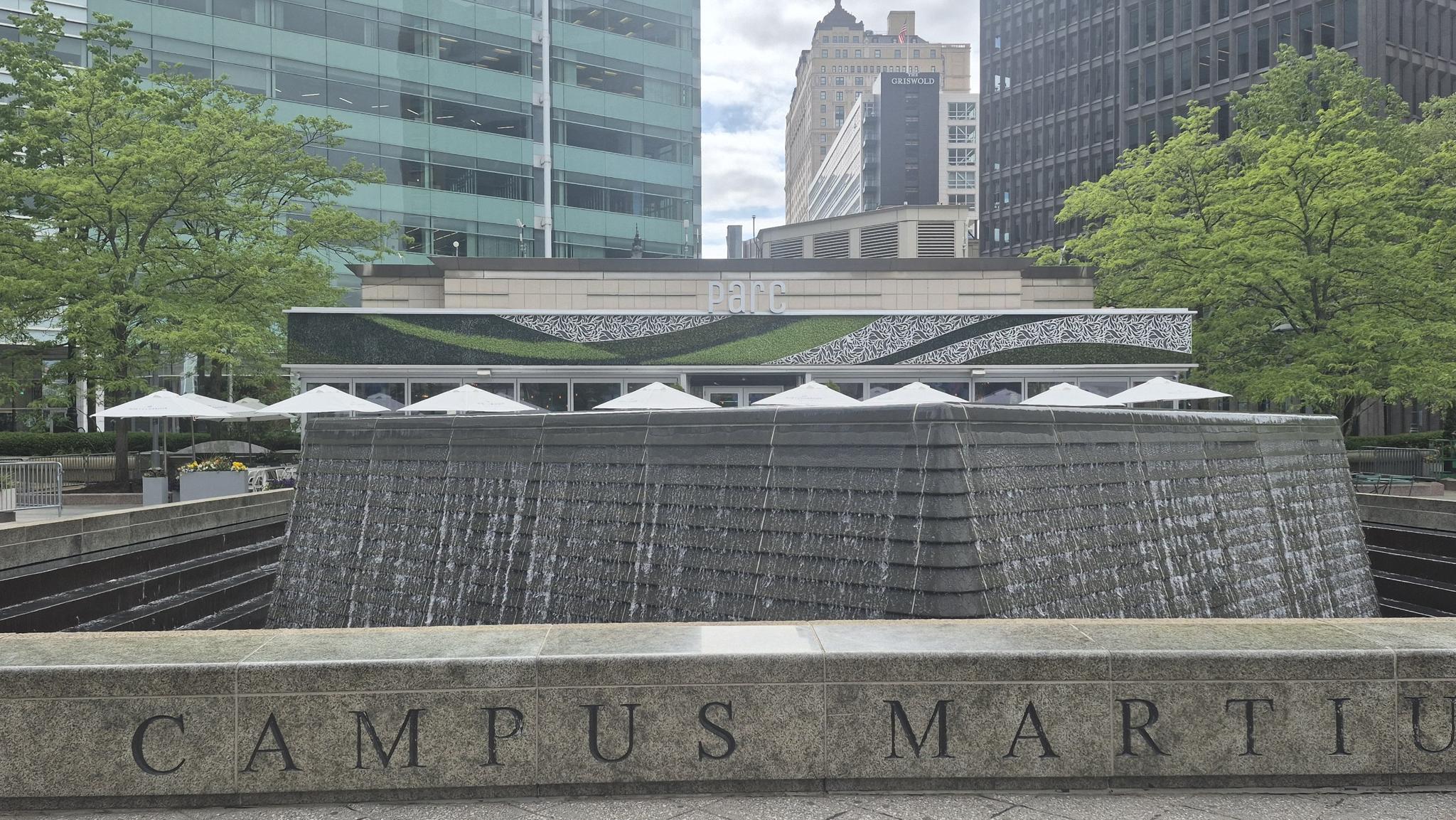 Large stone fountain with water cascading, in front of a modern building.