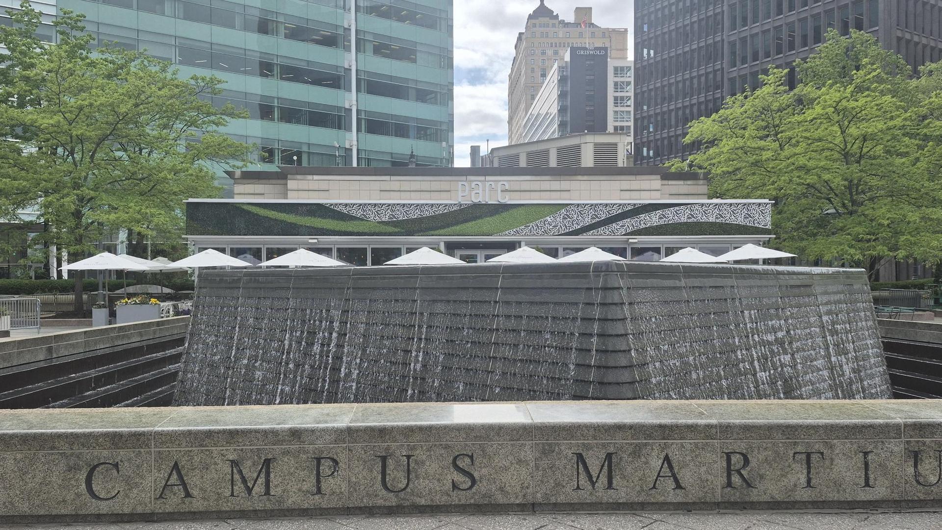 Large stone fountain with water cascading, in front of a modern building.