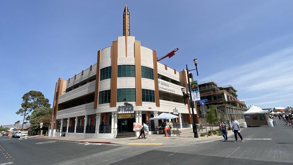 An Art Deco building on a sunny street corner with people walking.