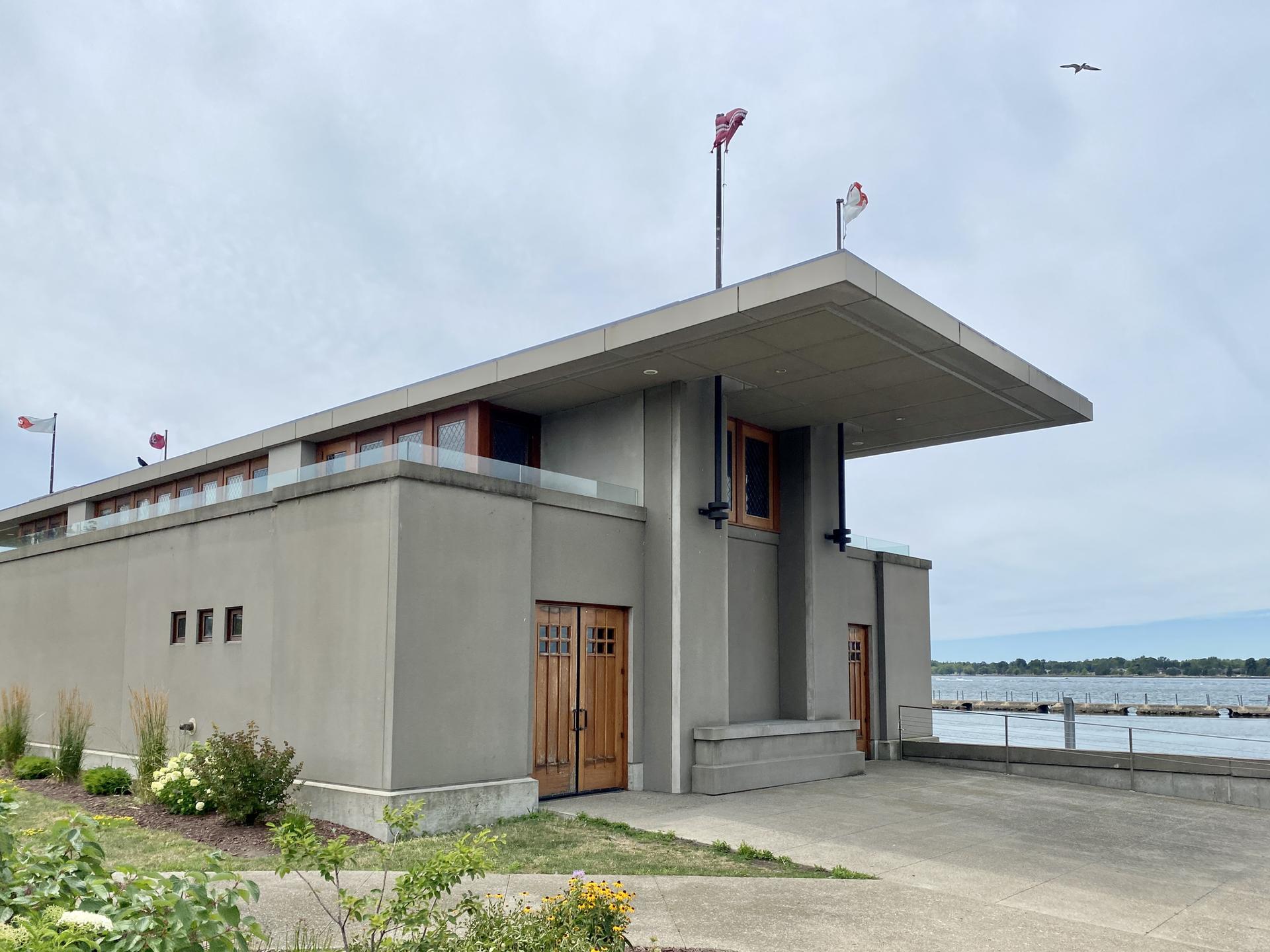 Modern concrete building with a flat roof next to a large body of water.
