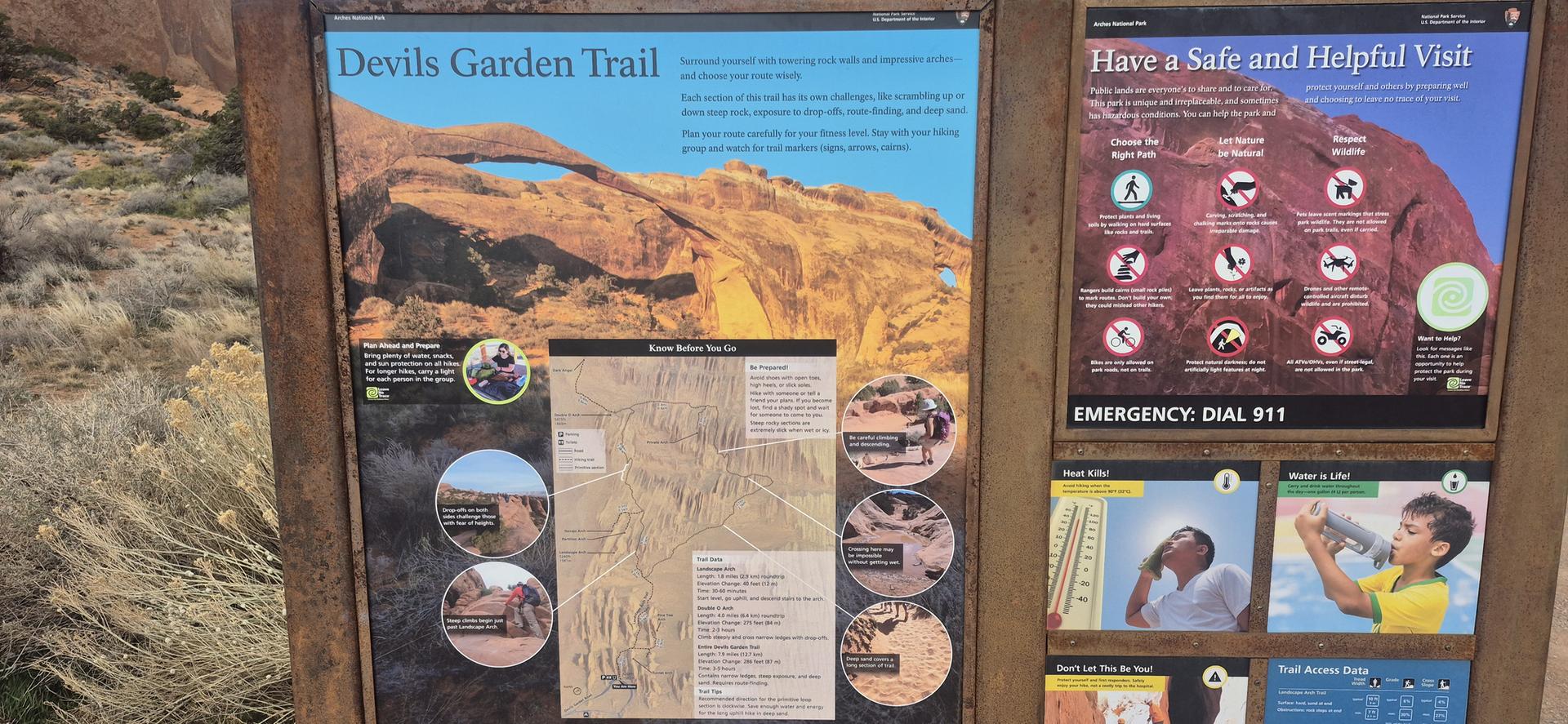An outdoor information board with maps and safety tips in a desert setting.