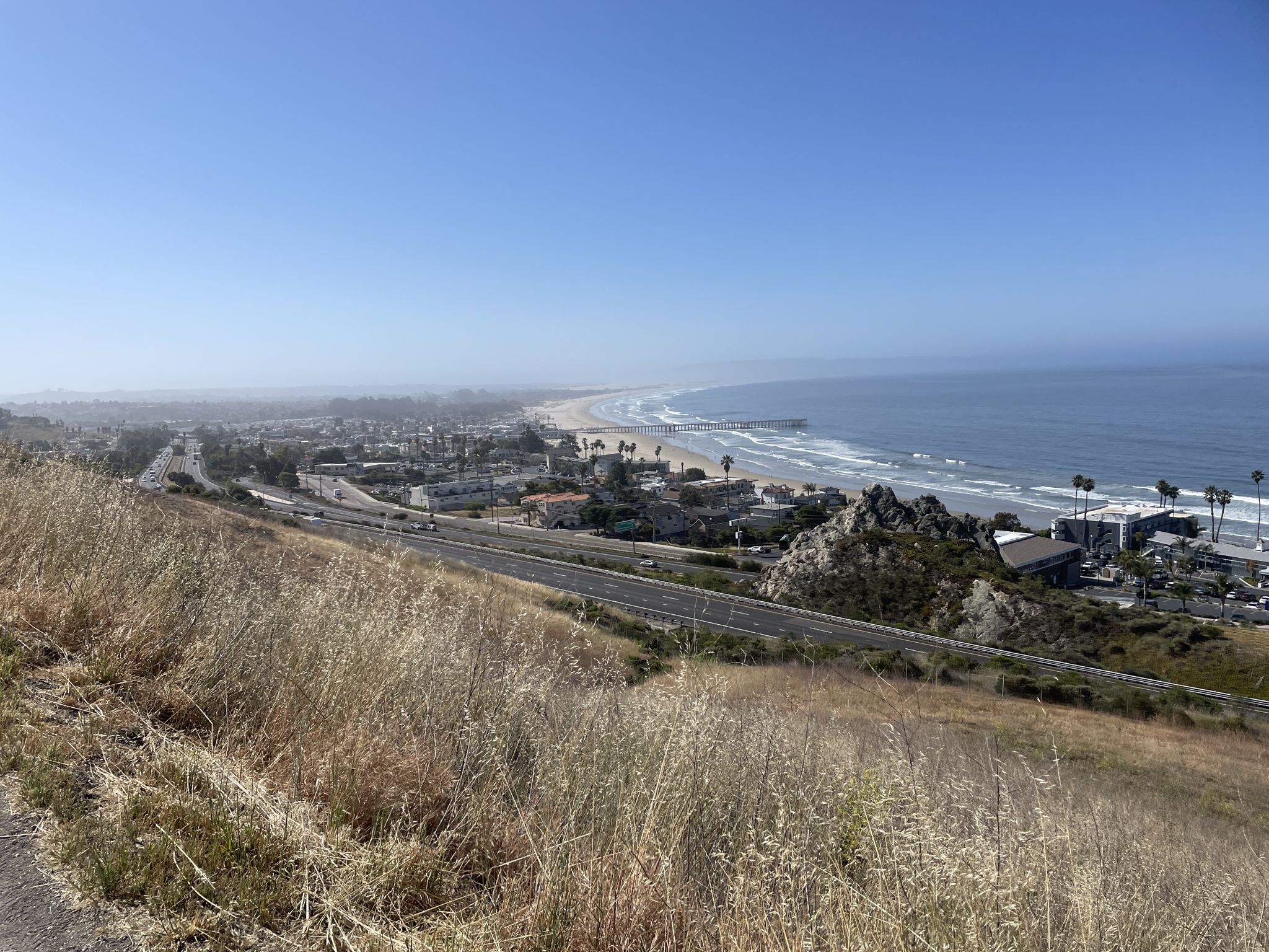 Elevated view of a coastal town, beach, and highway under bright blue skies. - Bridge over Pismo Creek – Lone Oak loop from Grover Beach