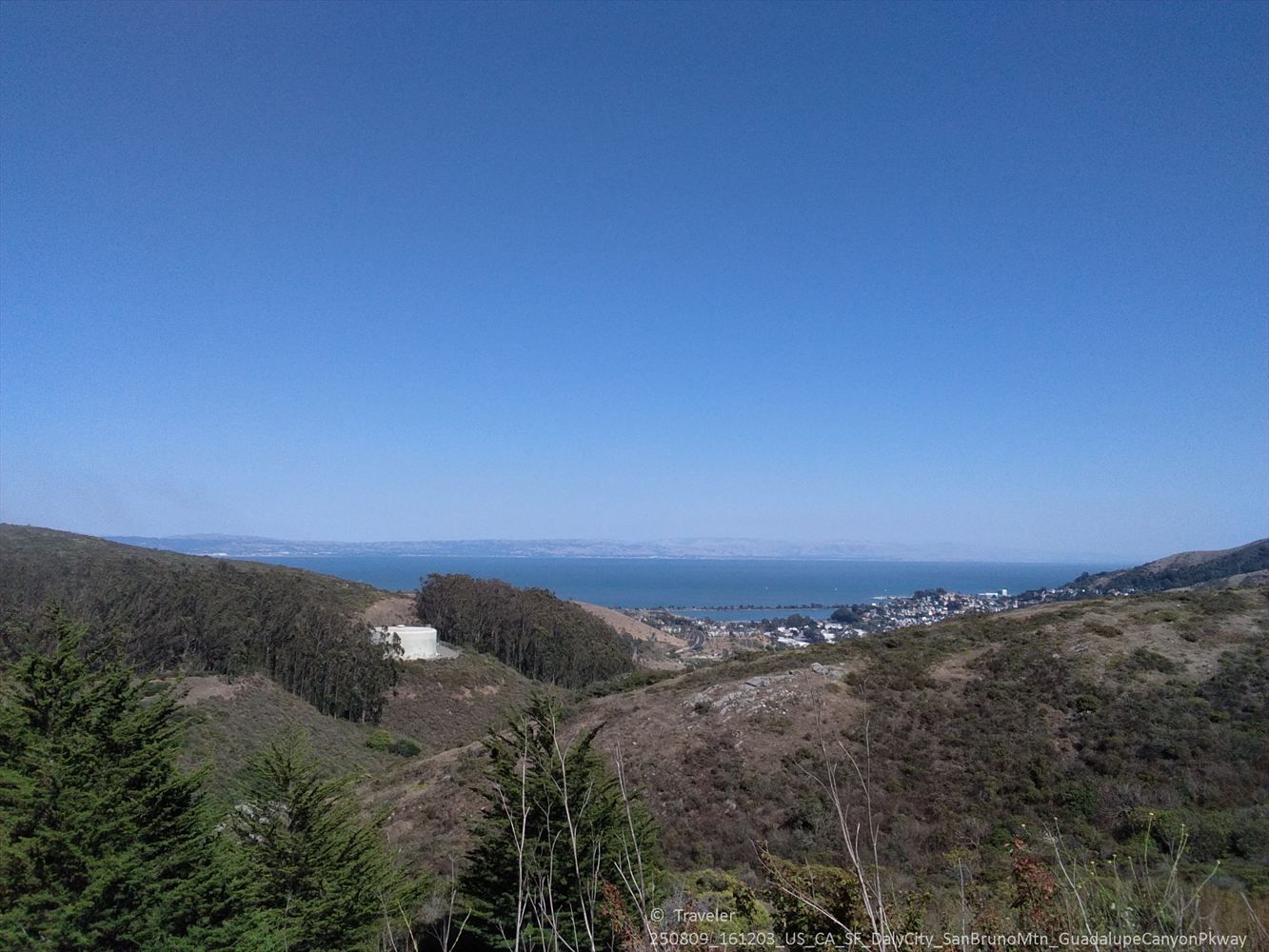 Valley with forested hills, distant ocean, and a small coastal town. - Guadelupe Canyon Parkway loop from Colma