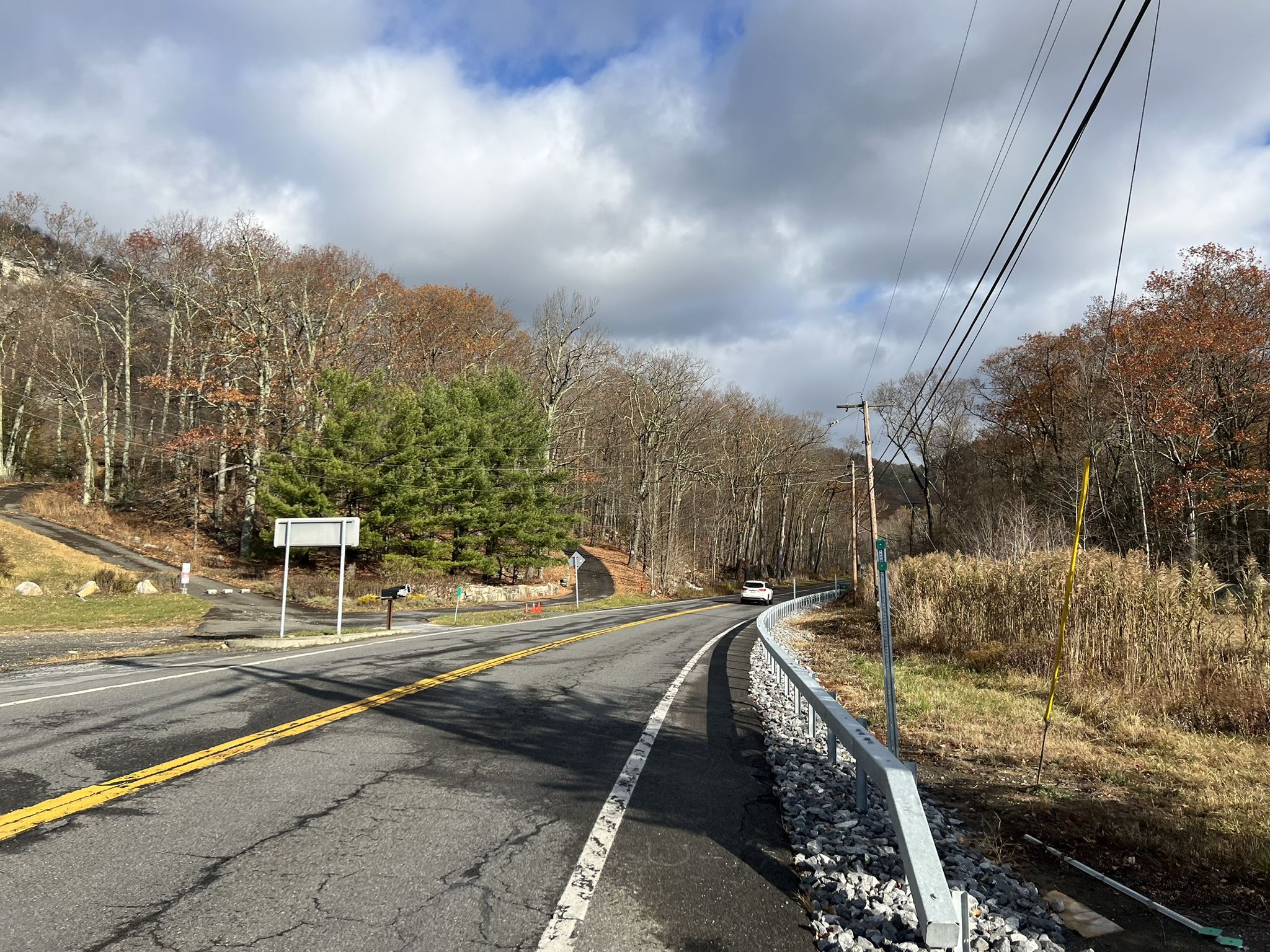Paved road with a guardrail, curving through autumn trees under a cloudy sky. - Gardiner to Minnewaska State Park Preserve loop