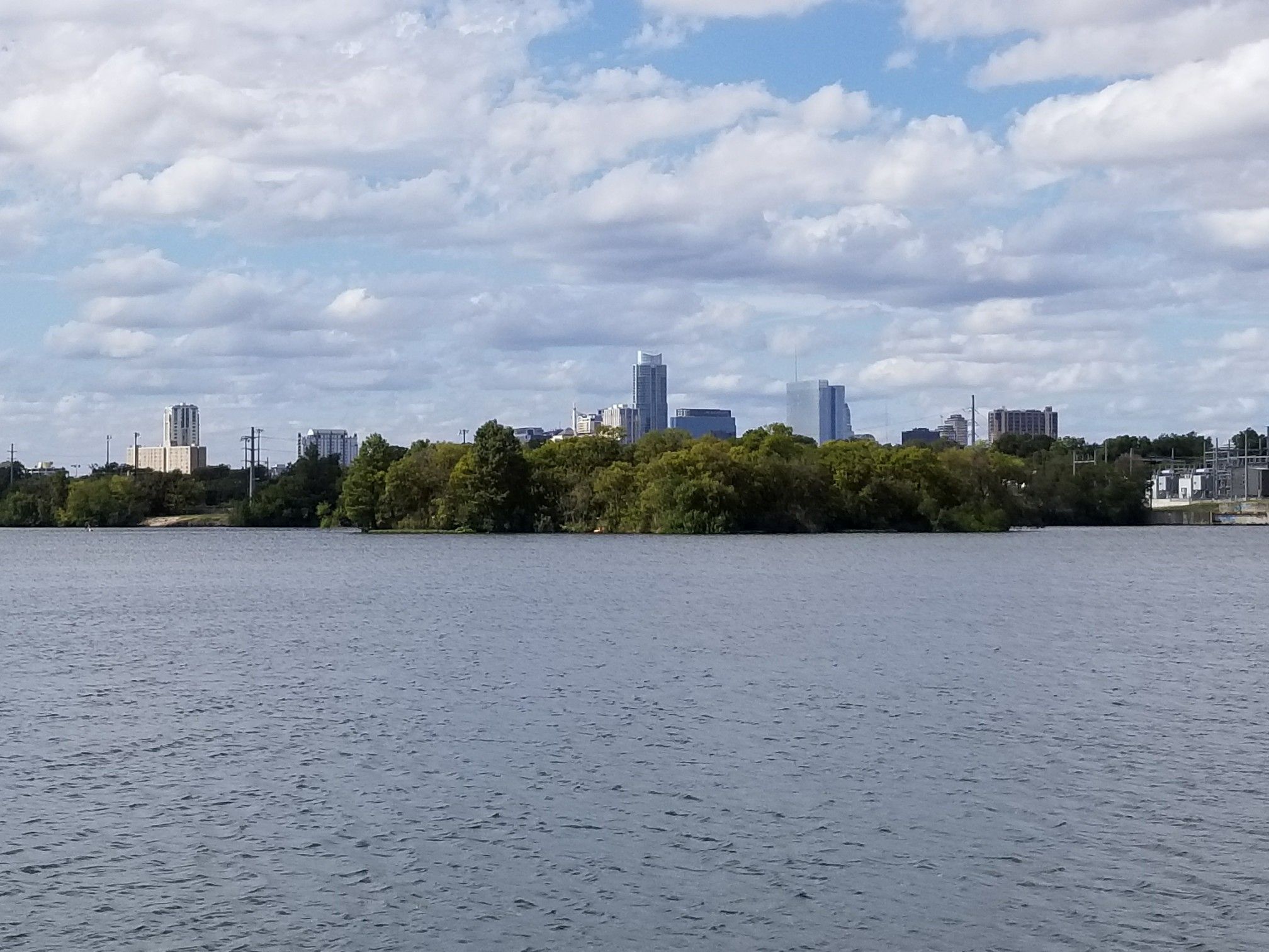 City skyline visible across a wide body of water under a partly cloudy sky. - Boardwalk – Longhorn Point loop from Huston-Tillotson University