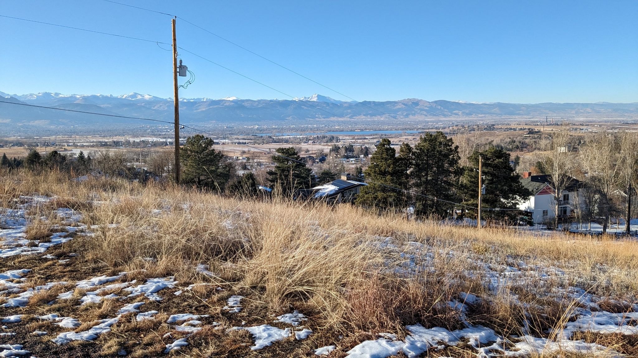 Snowy field with dry grass, distant mountains, and power lines under clear sky. - Davidson Mesa Trail – Davidson Mesa loop from Paragon Estates