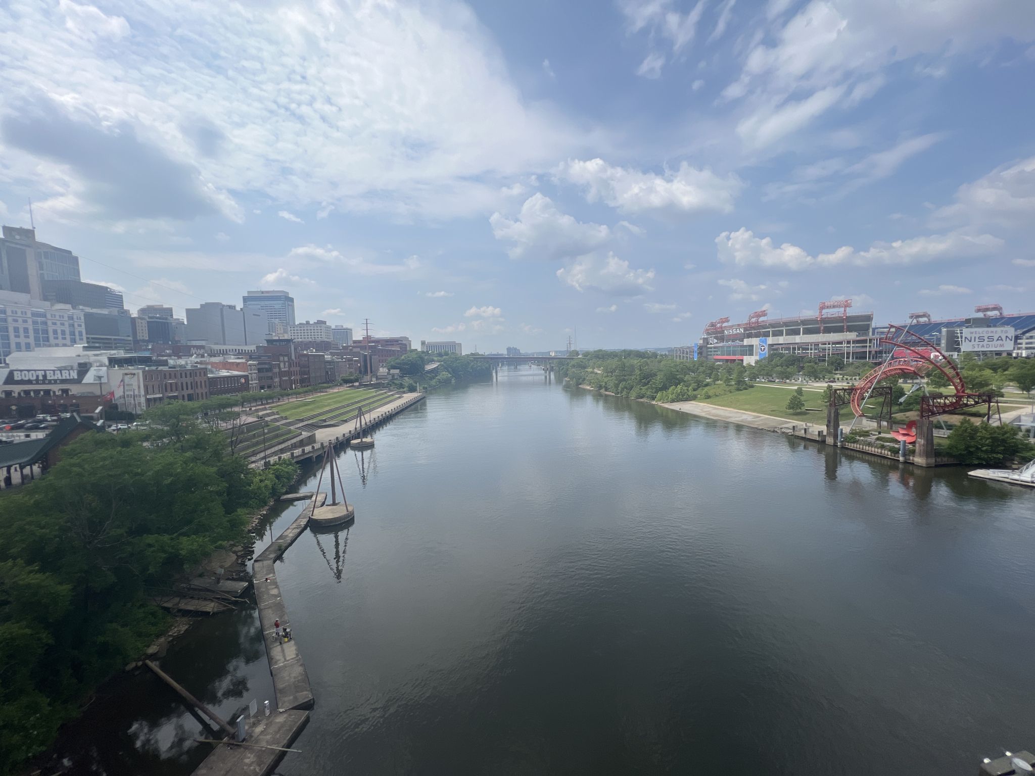 Wide river through a city with buildings and a stadium, cloudy sky. - Downtown Nashville and Centennial Park loop via the Cumberland River Greenway