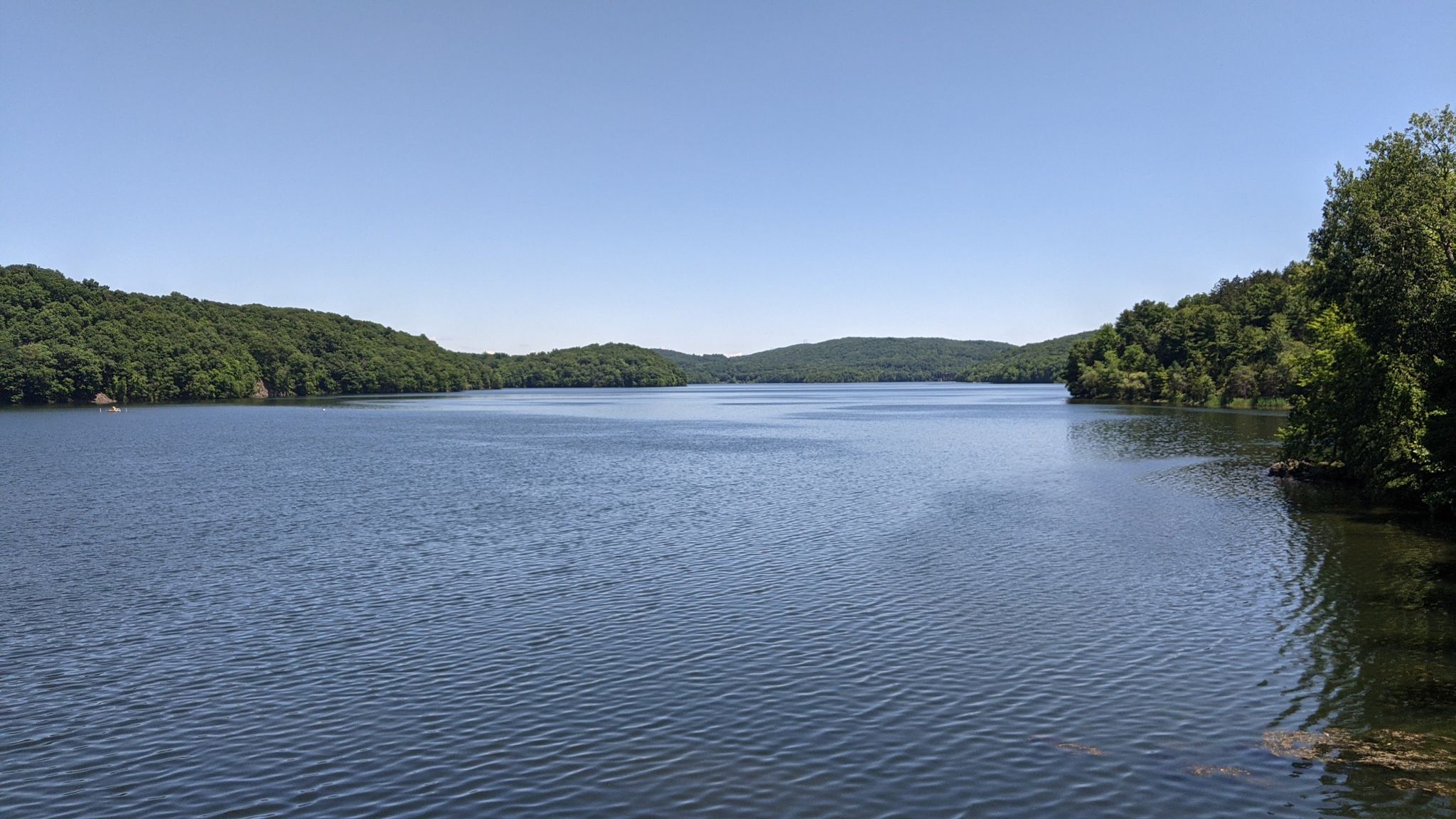 Expansive calm lake surrounded by distant green, forested hills under clear sky. - New Croton Dam – Old Croton Dam Road Bridge loop from Croton-Harmon