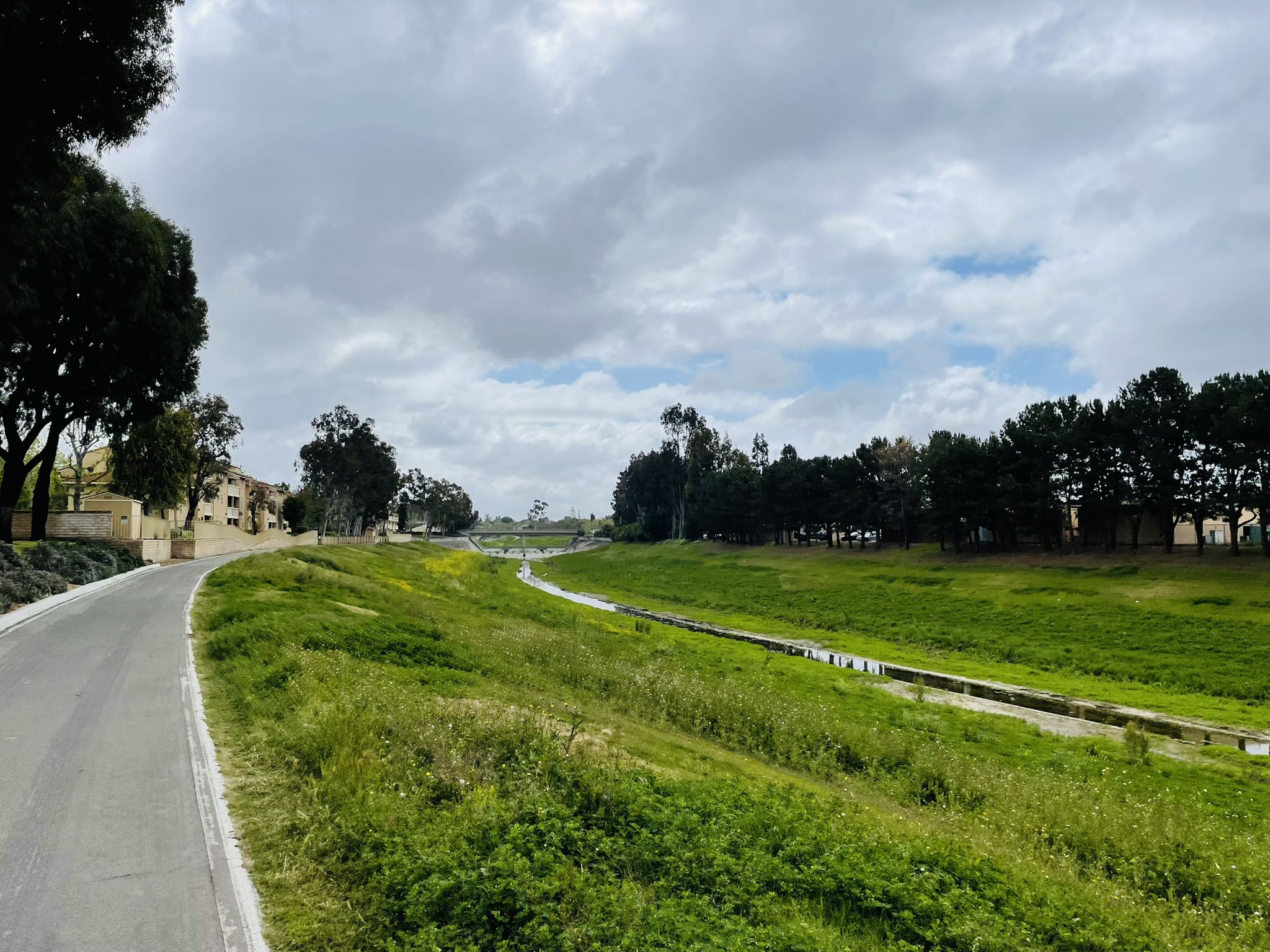 A paved path alongside a wide, green field under a cloudy sky. - San Diego Creek – San Diego Creek Bike Trail loop from Irvine