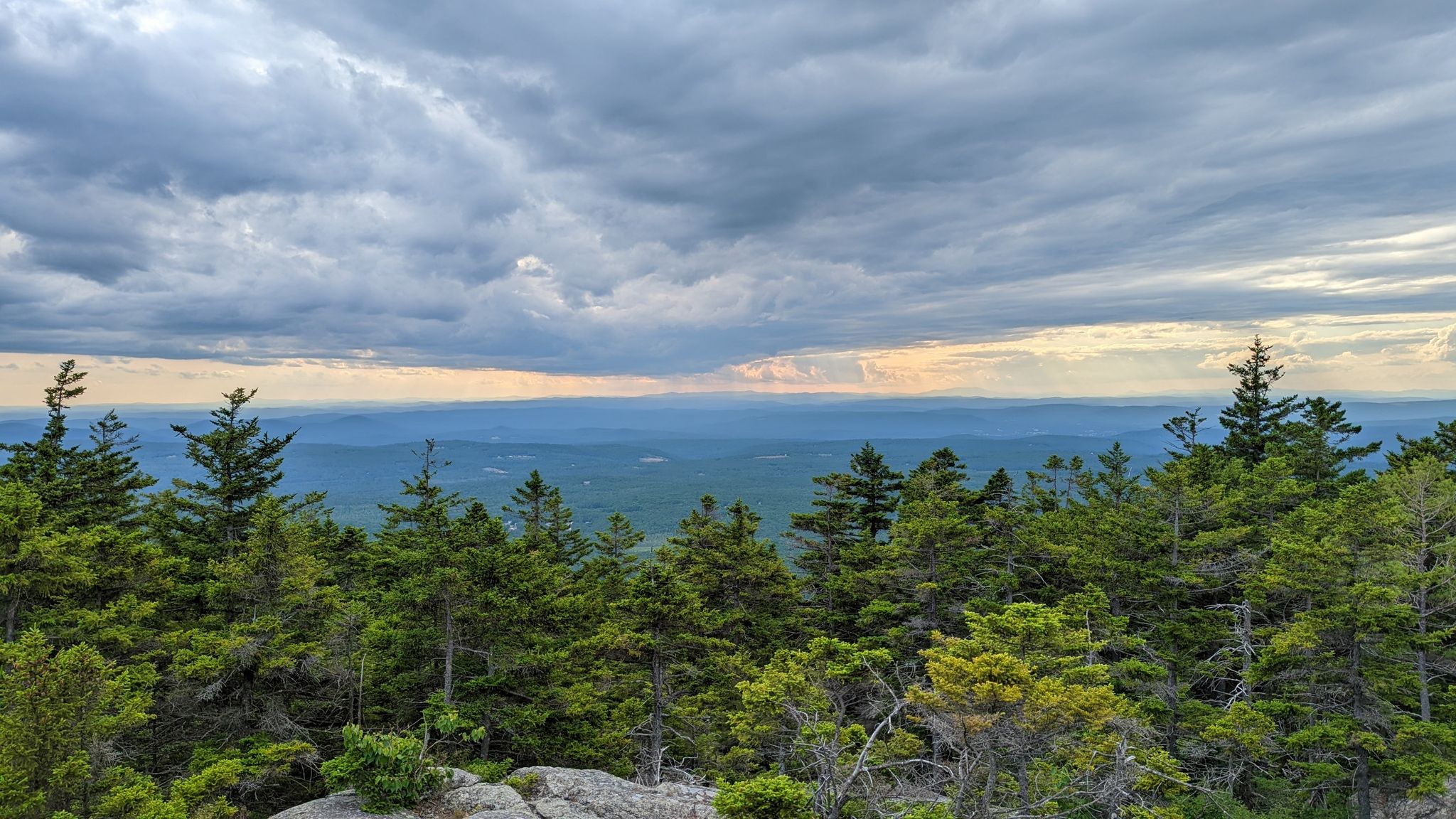 Mountain vista with dense green trees under a dramatic cloudy sky. - Marlboro Trail