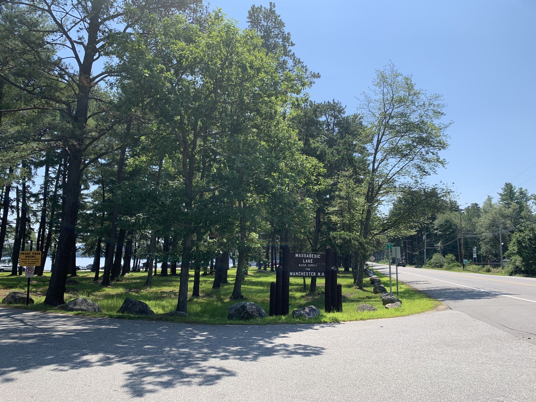 Sunny road intersection leading into a wooded area with a park sign. - Massabesic Lake – Clark Pond loop from Manchester