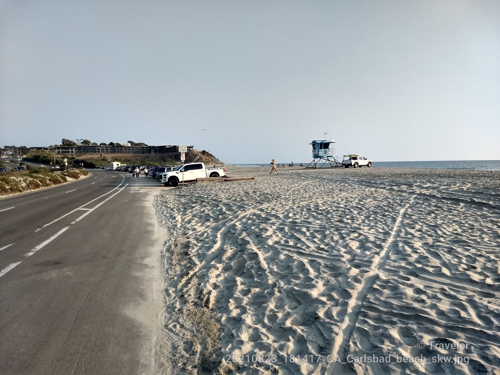 Sandy beach with a lifeguard tower, parked cars, and a road. - South Carlsbad State Beach