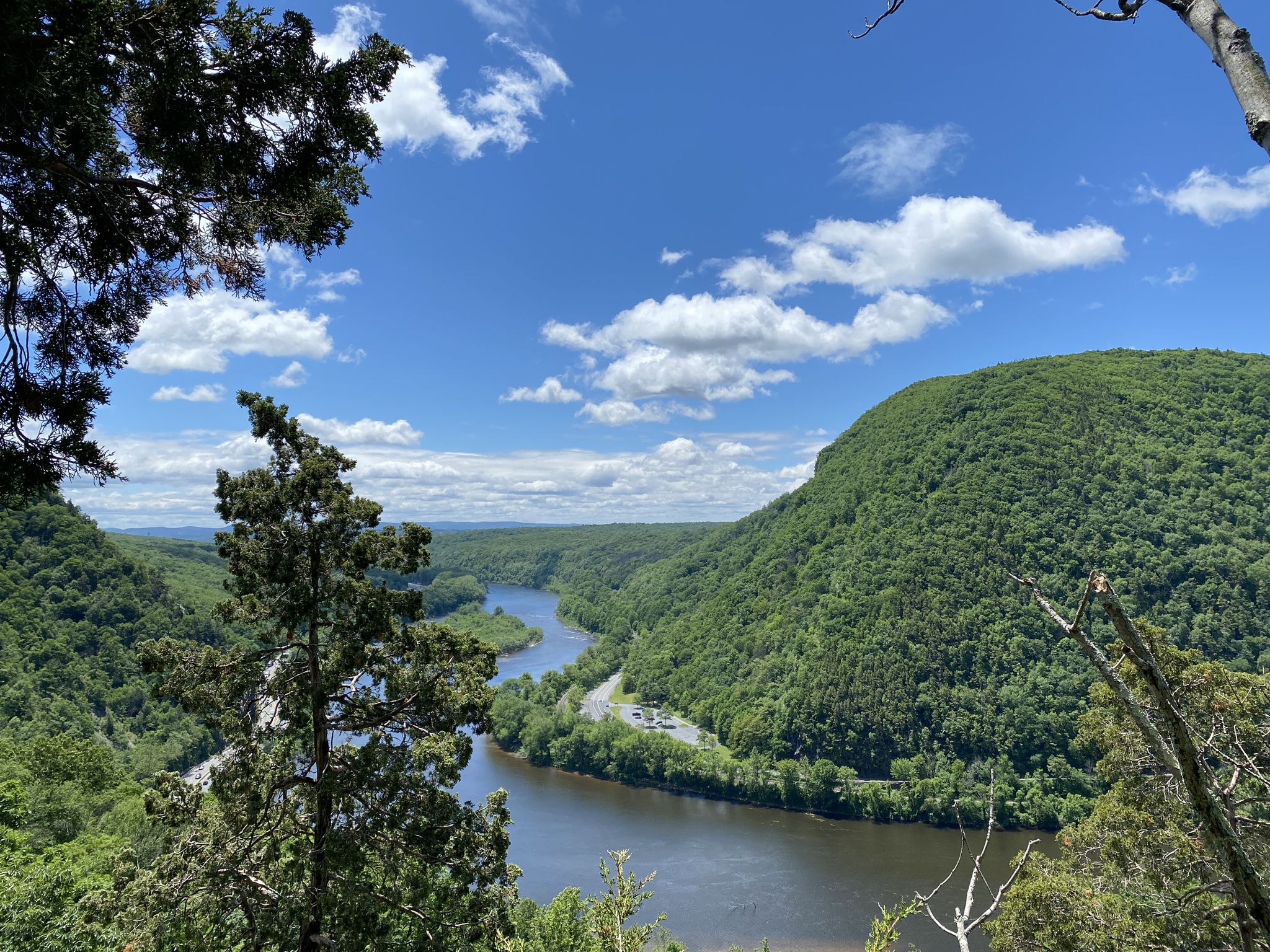 River winding through lush green mountains under a bright blue sky. - Mount Tammany and Sunfish Pond Loop