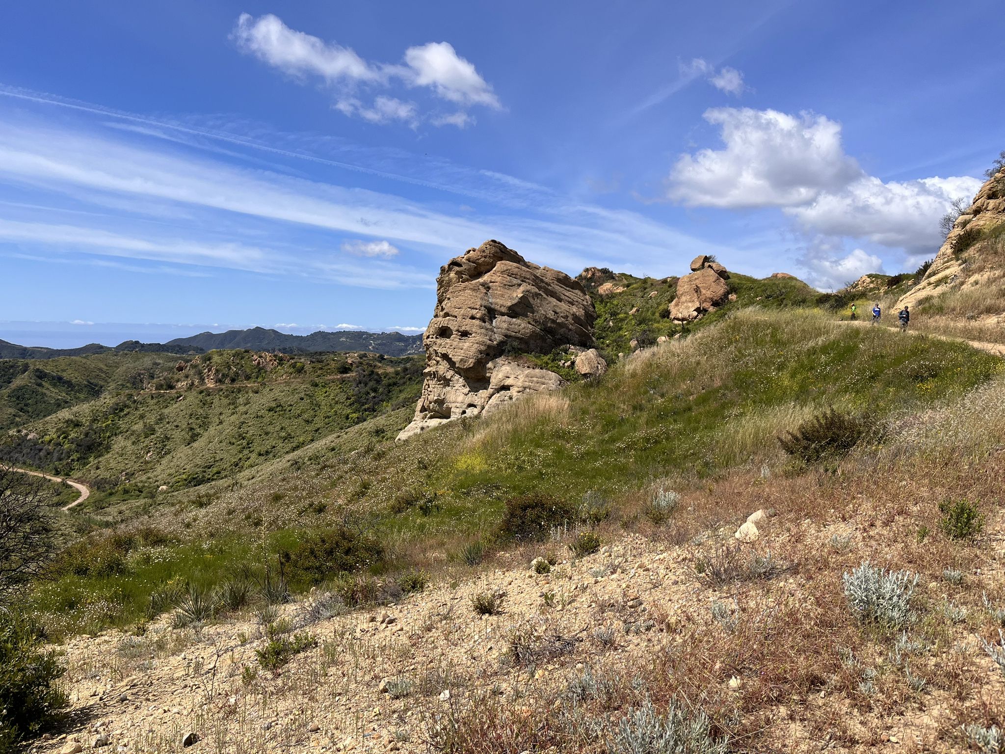 Rocky outcrop on a green hillside under a bright blue sky with clouds. - Eagle Rock – San Vicente Mountain Viewpoint loop from Red Rock Canyon Park
