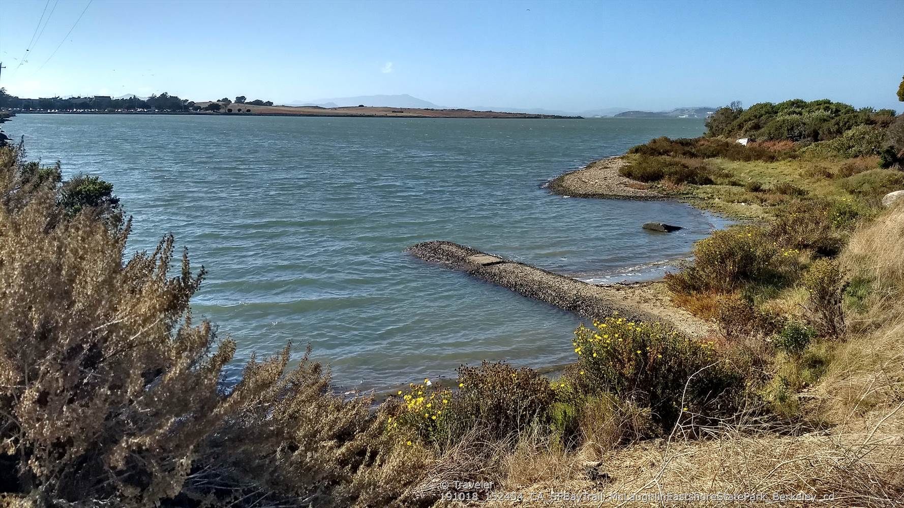 A calm water inlet with a rocky shore and dry, bushy vegetation. - Aquatic Park – Aquatic Park North Trailhead loop from Downtown Berkeley