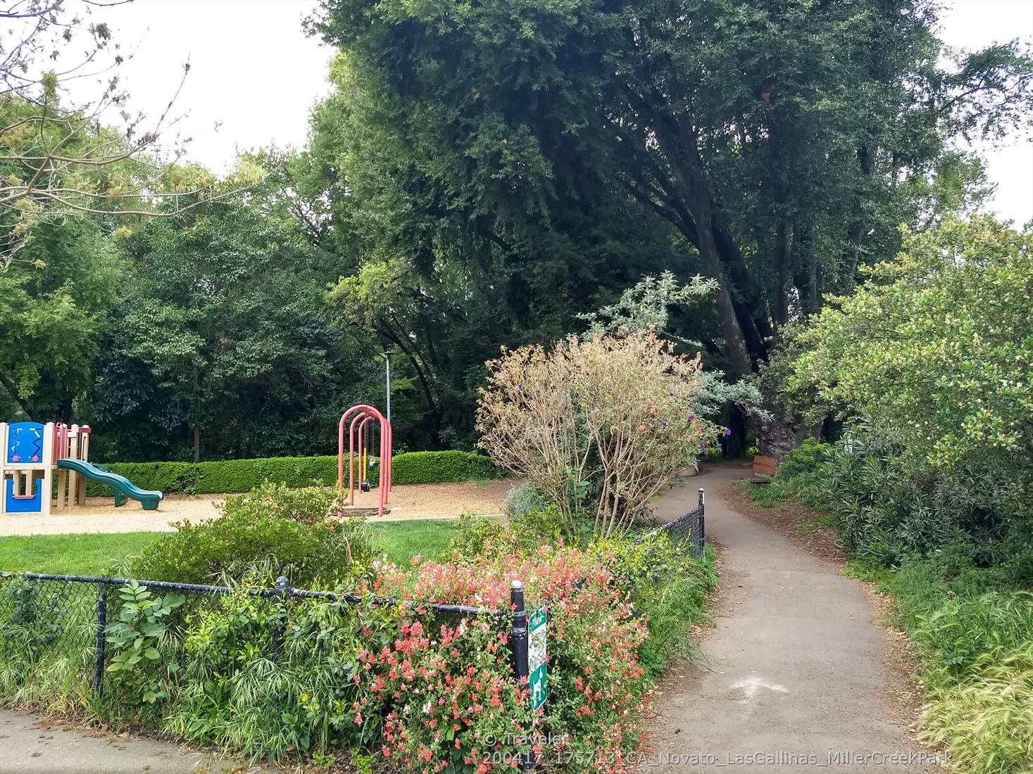 A playground with a blue slide and red swings next to a dirt path. - San Francisco Bay Trail Loop