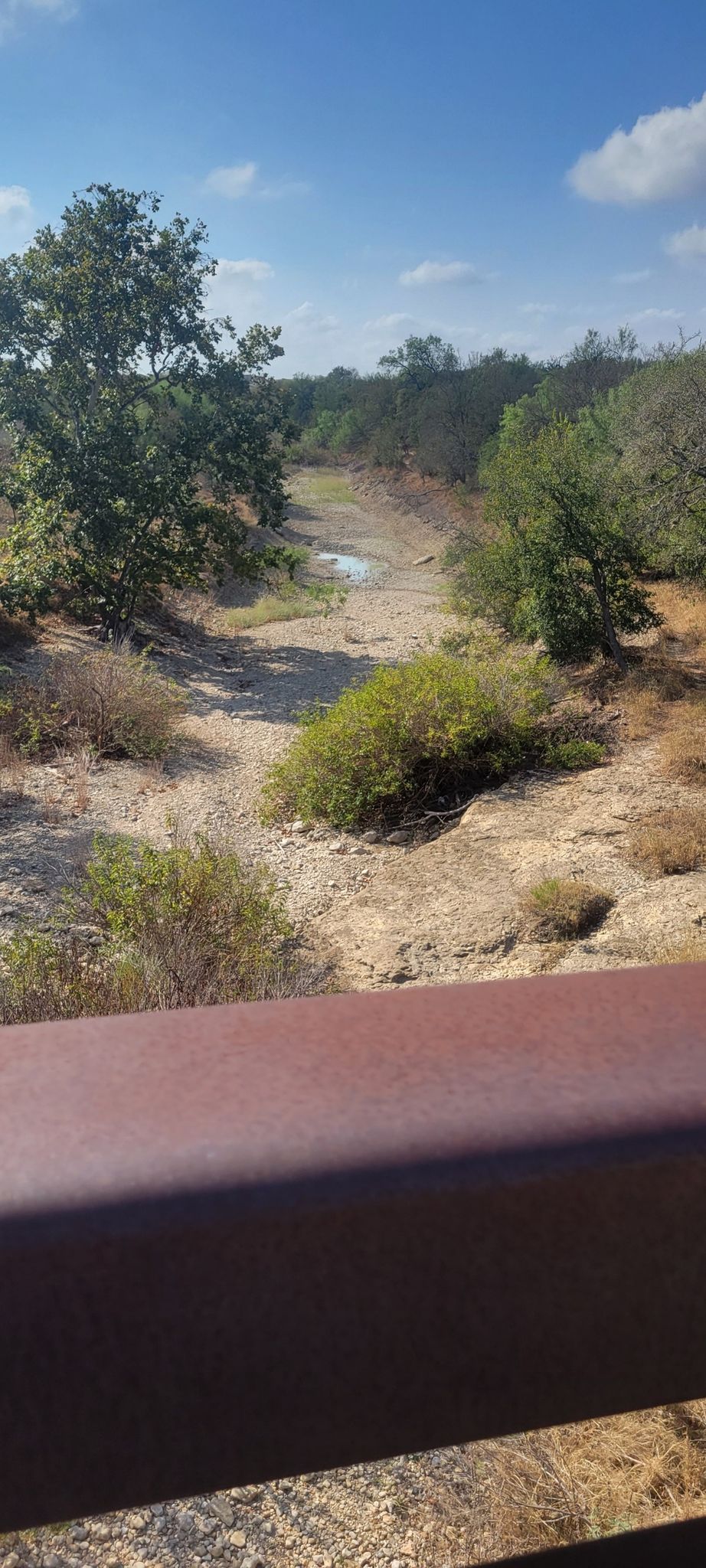 An elevated view of a dry riverbed or wash surrounded by sparse trees. - Drinking Fountain at Fox Park – Bamberger Nature Park loop from Six Flags Fiesta Texas