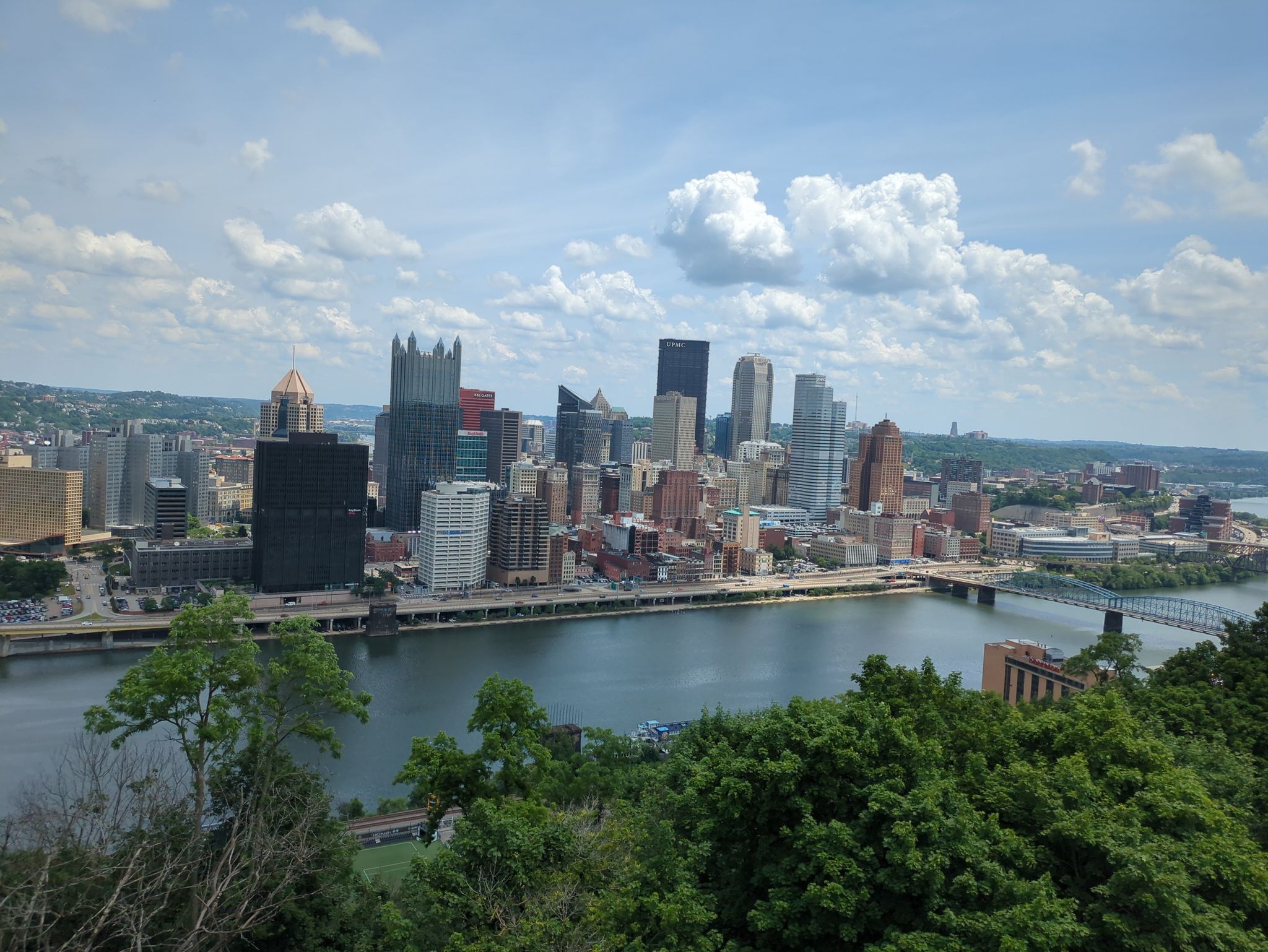 Panoramic city skyline and river from a high vantage point, sunny day. - Andy Warhol Bridge – View of the Andy Warhol Bridge loop from Dormont Junction