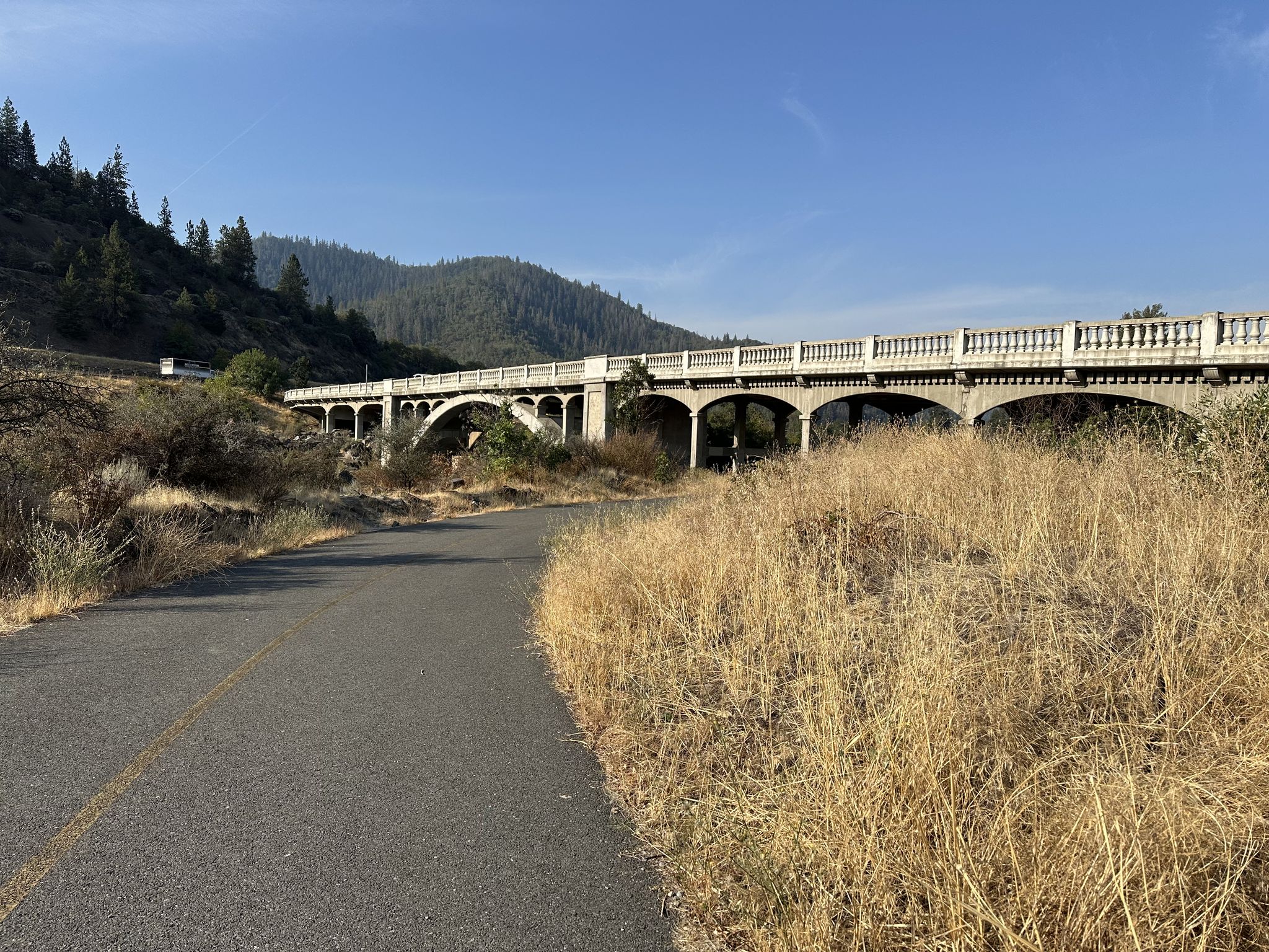 A large concrete arch bridge spans a dry landscape under a clear sky. - Evans Creek loop