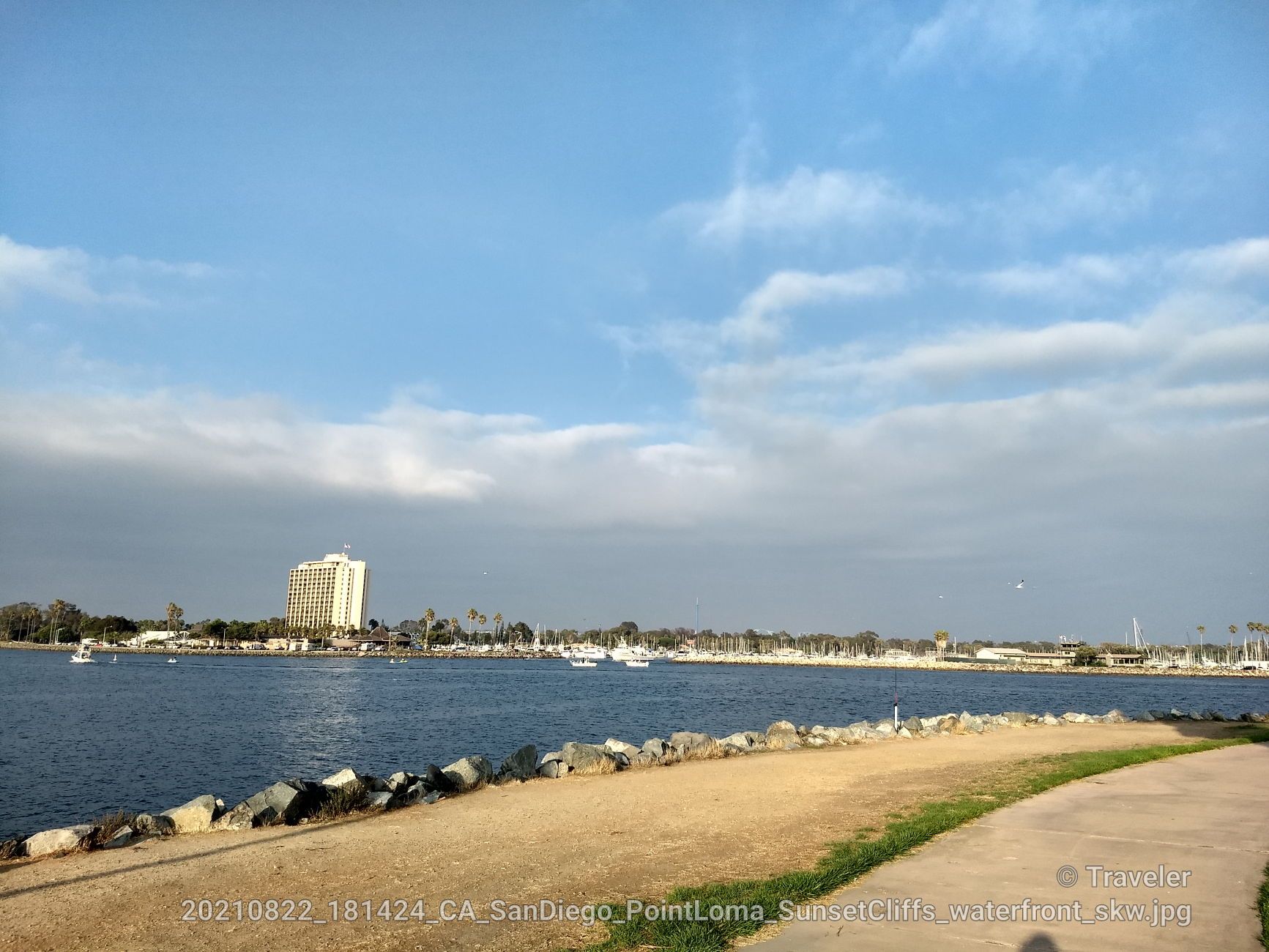 Waterfront view with boats on blue water and a tall building in distance. - Mission Bay Bike Path