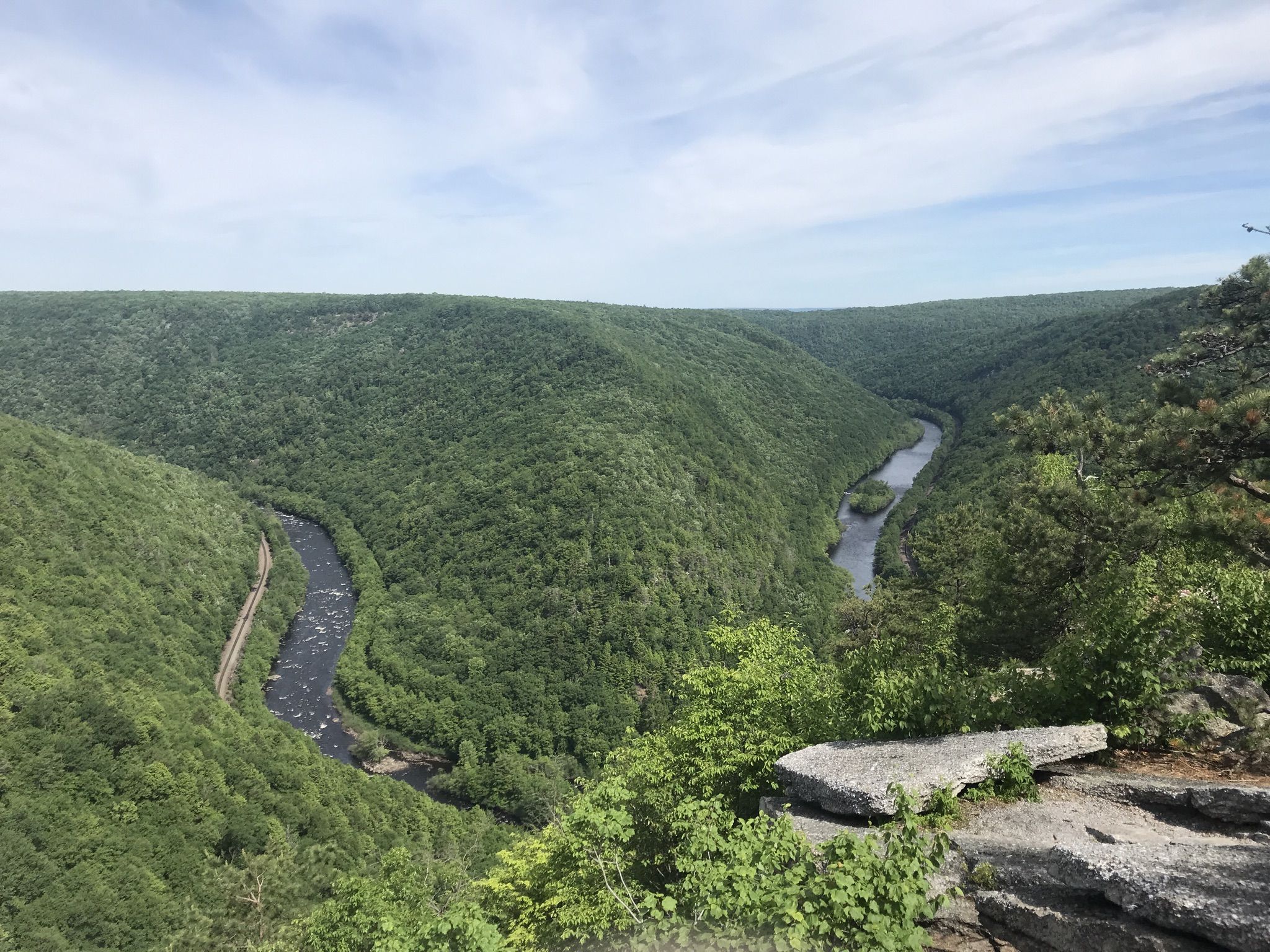River winding through a deep, green valley under a bright, cloudy sky. - Tank Hollow Trail