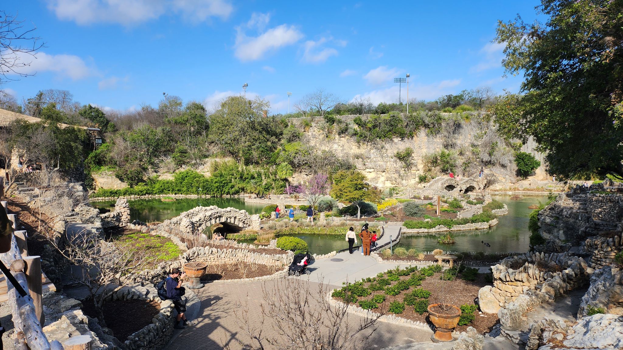 Sunny panoramic view of a landscaped garden with ponds and people. - Brackenridge Park – Japanese Tea Garden loop from San Antonio Zoo Eagle Train Station