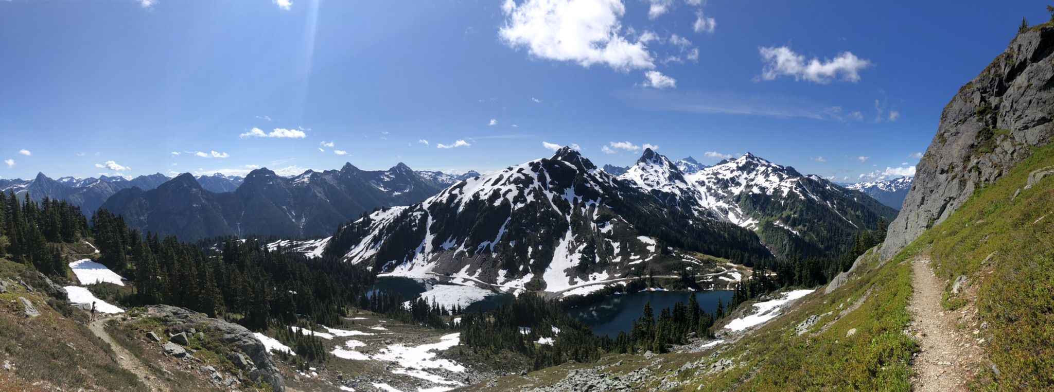 Panoramic view of rugged, snow-capped mountains, alpine lakes, and a winding trail. - Winchester Mountain Trail