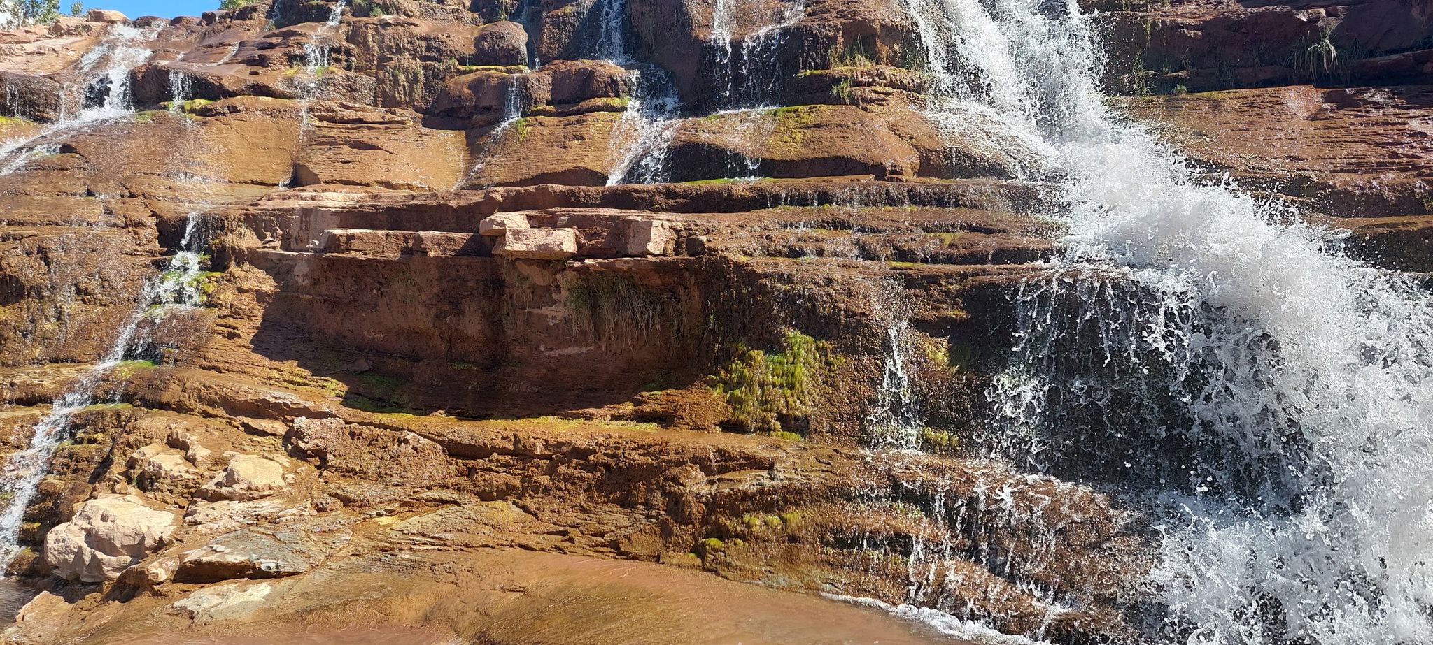 Close-up of multiple waterfalls cascading down textured red rock formations. - Rattlesnake Gulch Trail