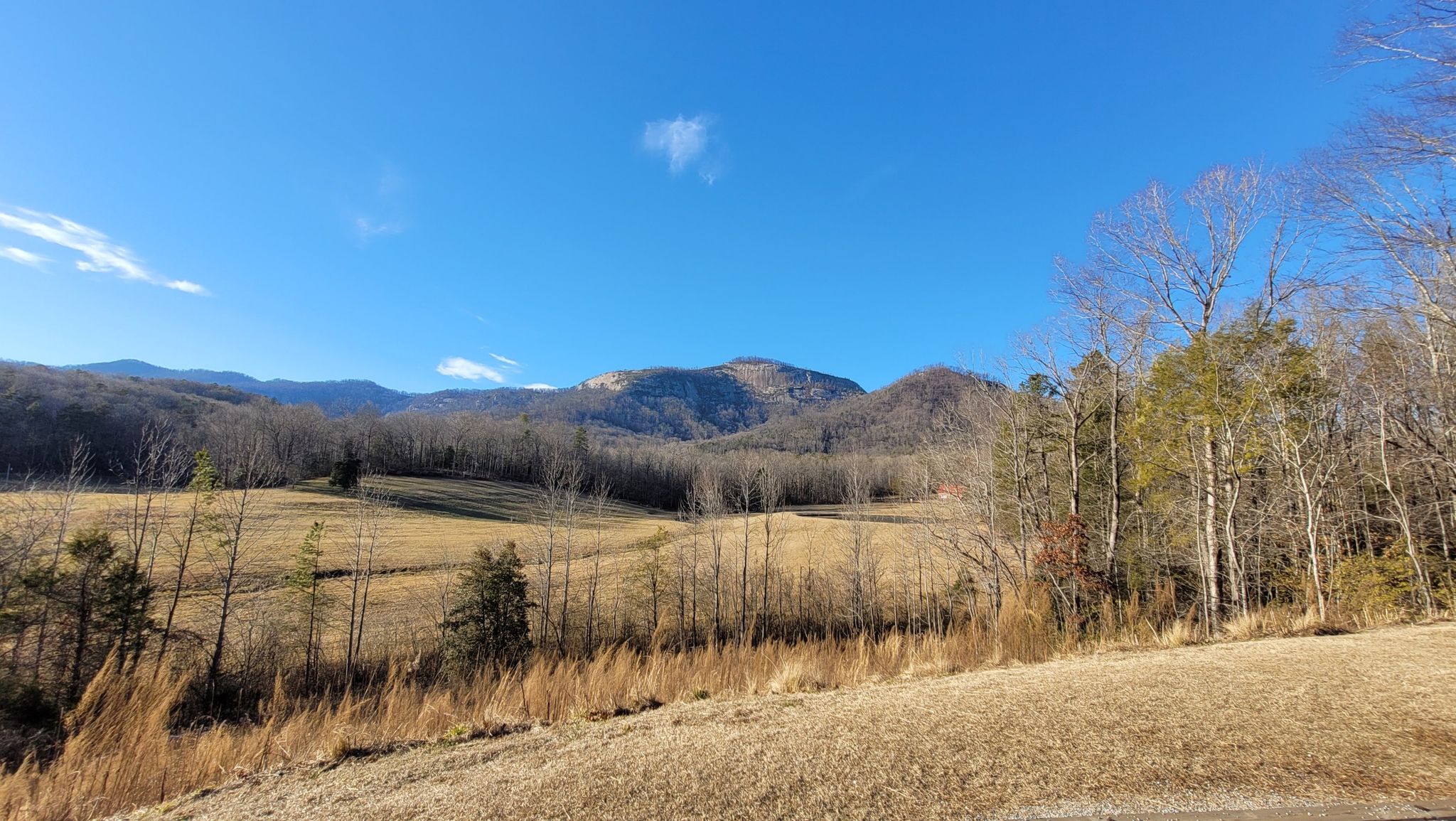 Sunny wide landscape of rolling hills and distant mountains under blue sky. - Table Rock Trail