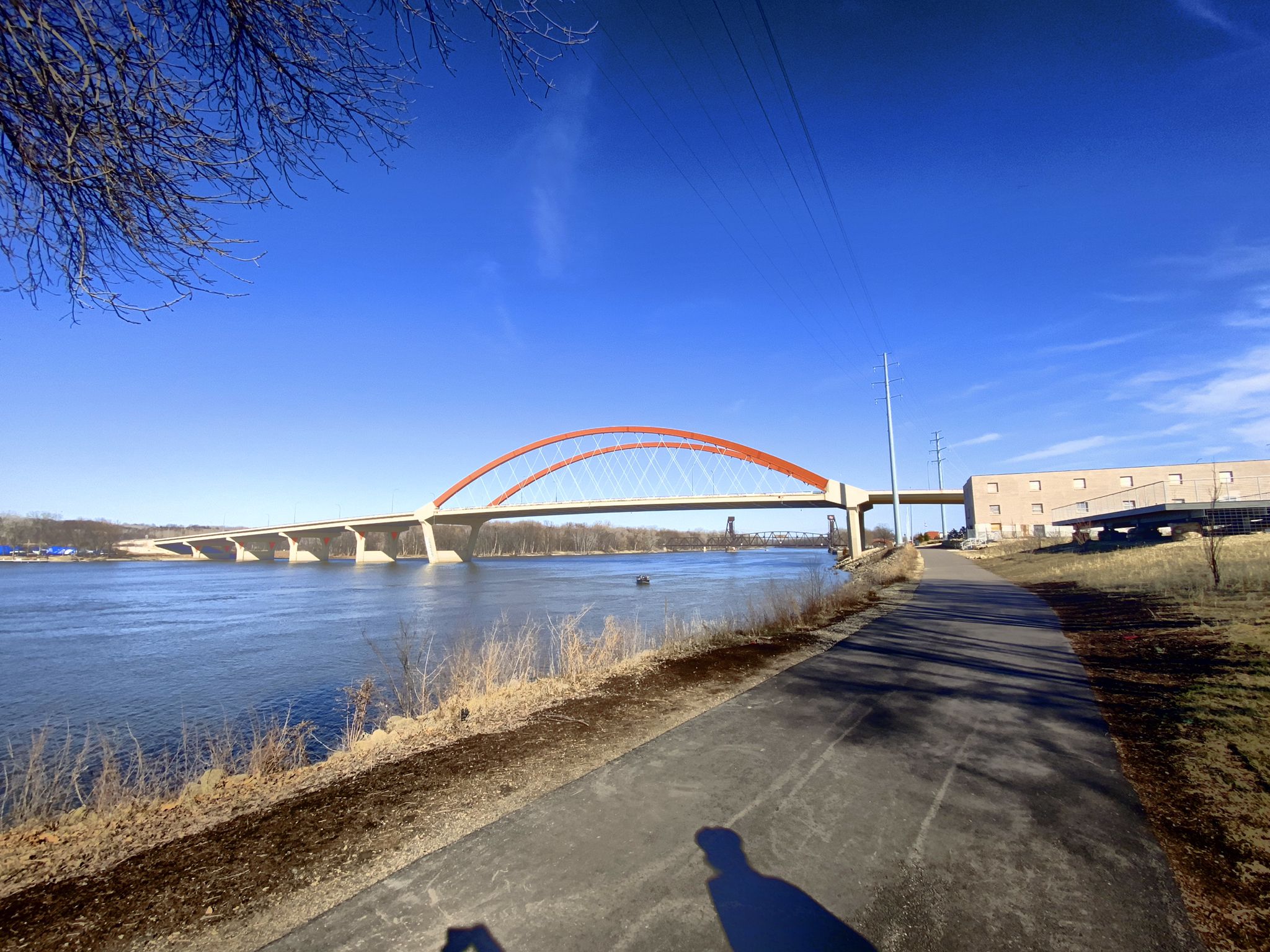 Red arch bridge over a wide river under a bright blue sky. - Vermillion River: Old Mill Park to Vermillion Slough