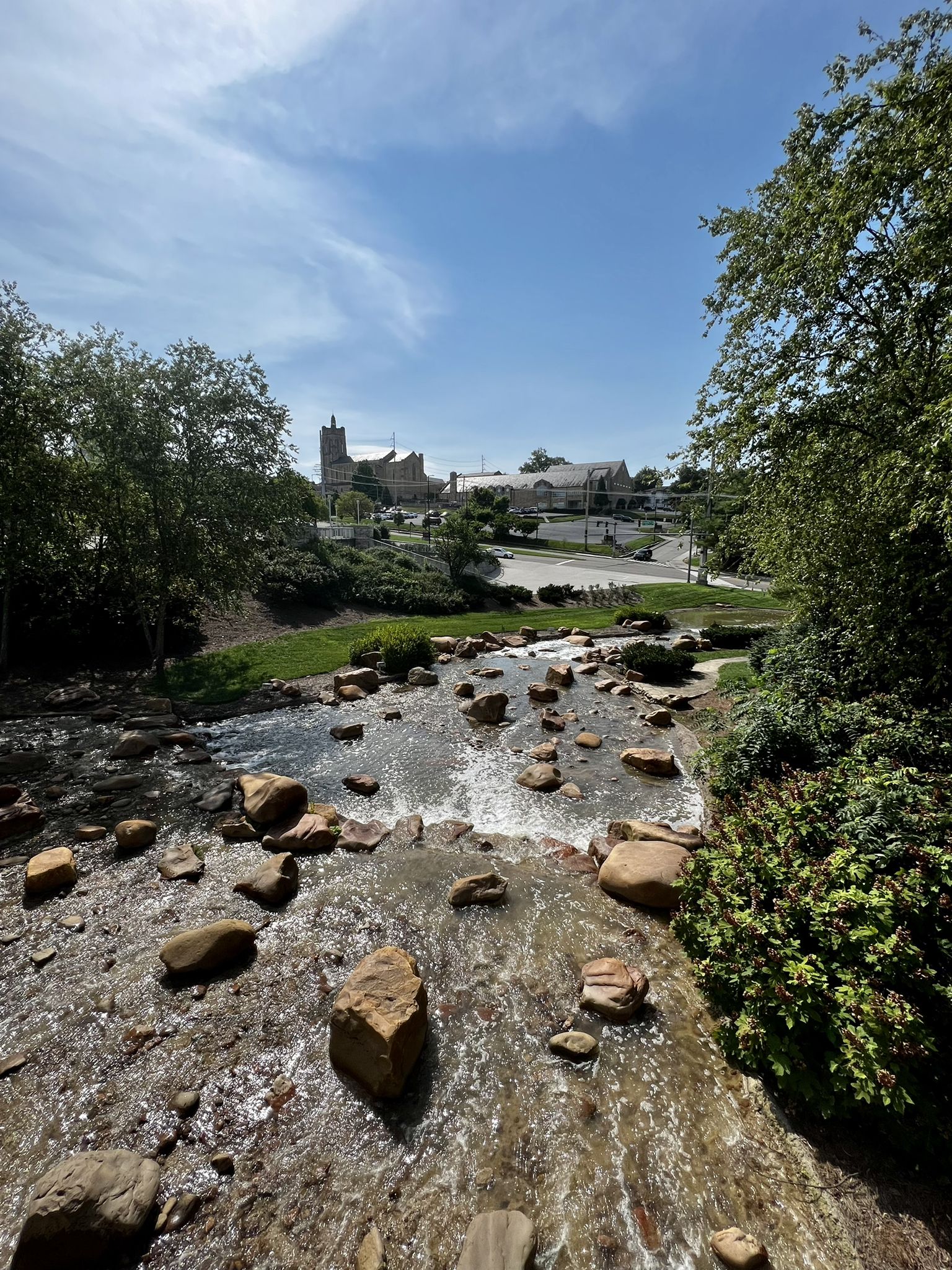 Rocky stream flowing under bright sun, with distant buildings and green trees. - Tyson Park – Third Creek Greenway loop from Parkridge