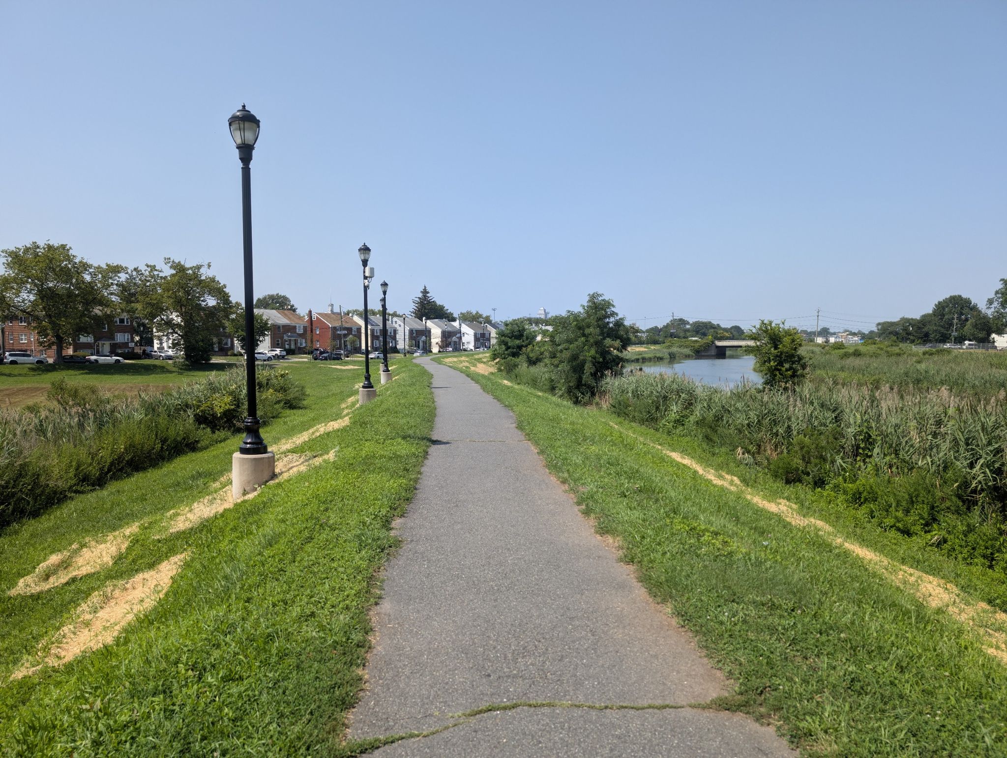 Paved path with lampposts beside a river and grassy banks on a sunny day. - Warinanco Park – Warinanco Park loop from North Elizabeth