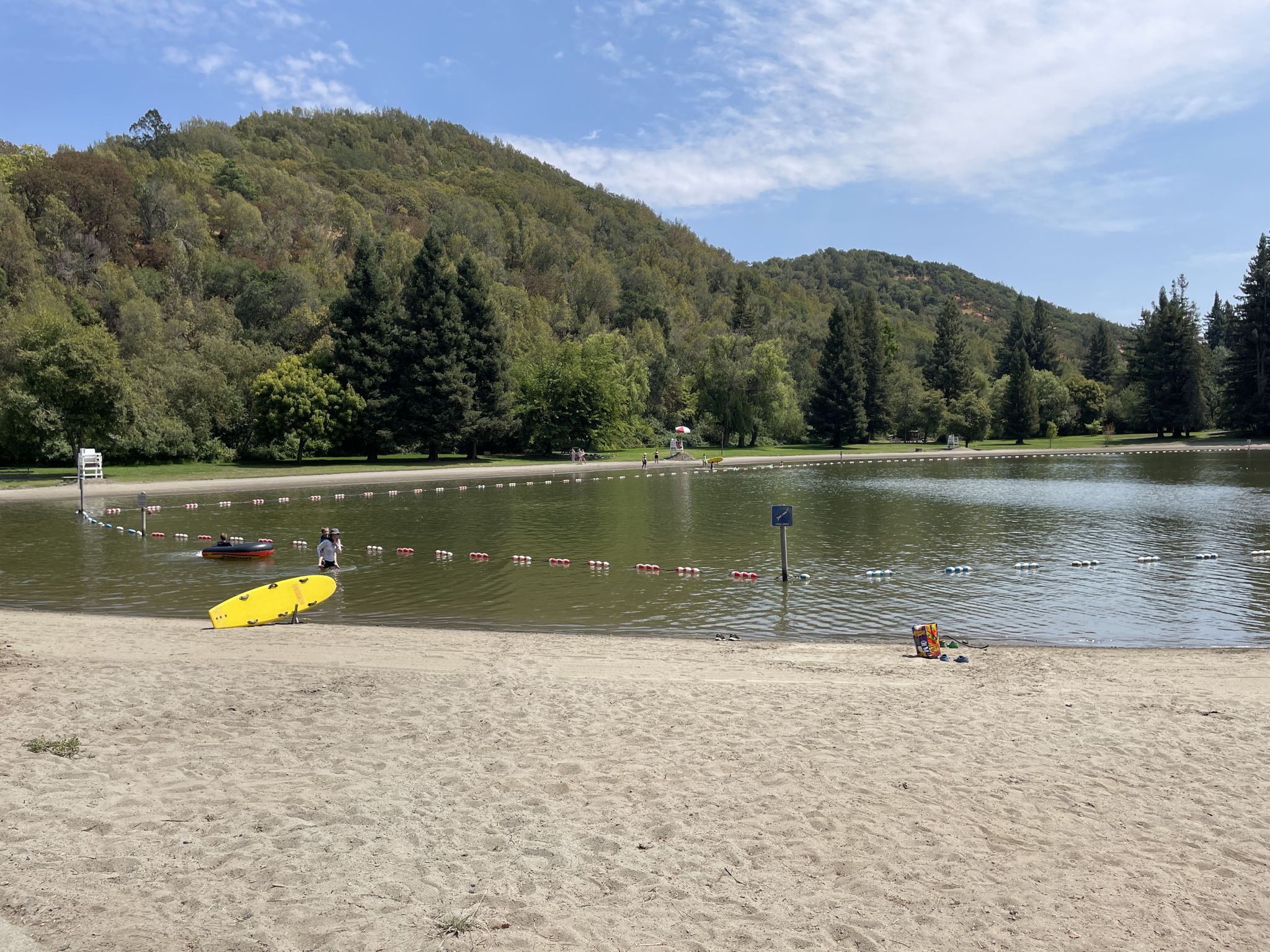 Sandy beach by a lake with a person near a yellow kayak and buoys. - Spring Lake loop