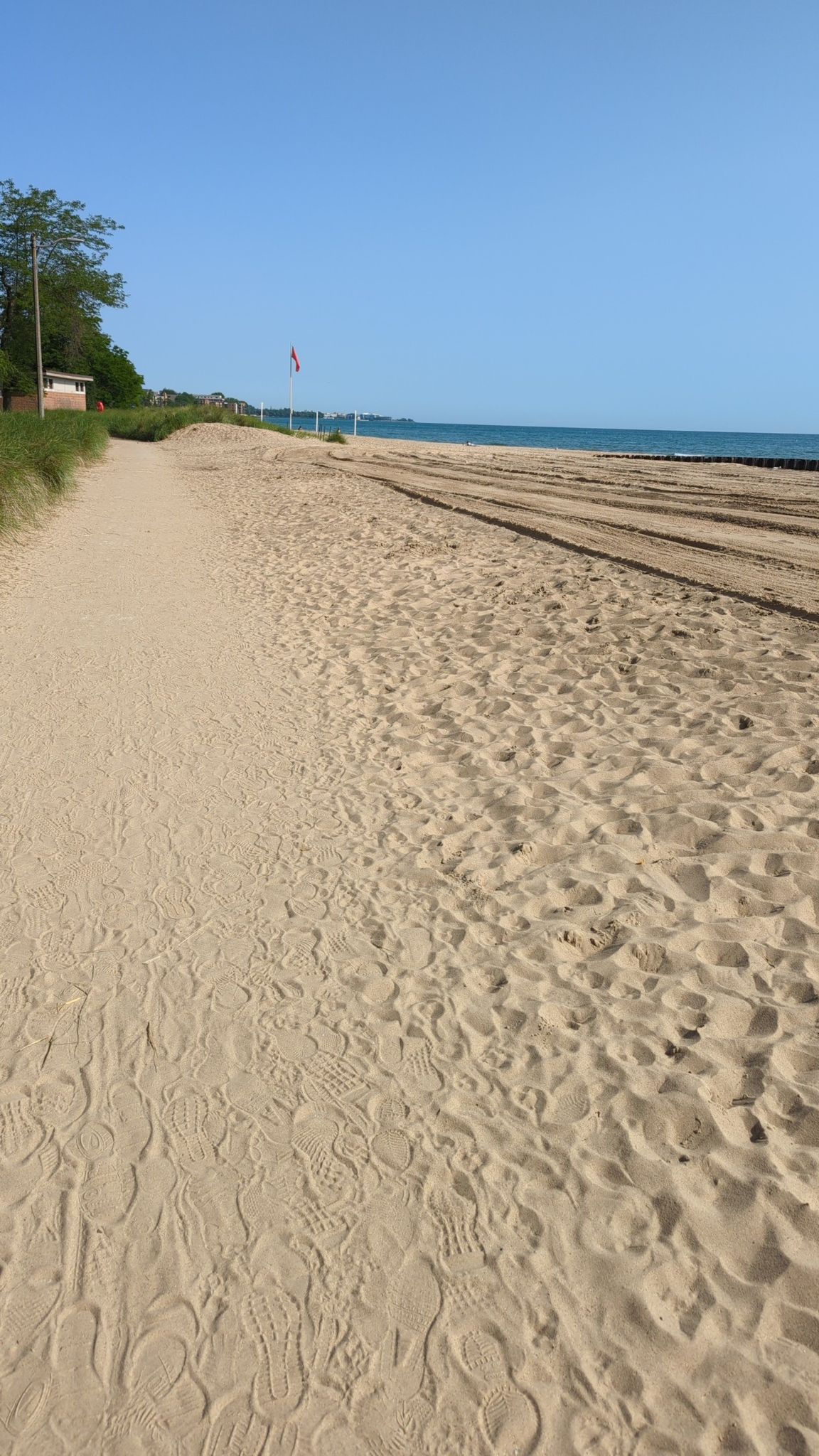 Bright sandy beach with a path, distant water, and blue sky. - Leone and Loyola Loop
