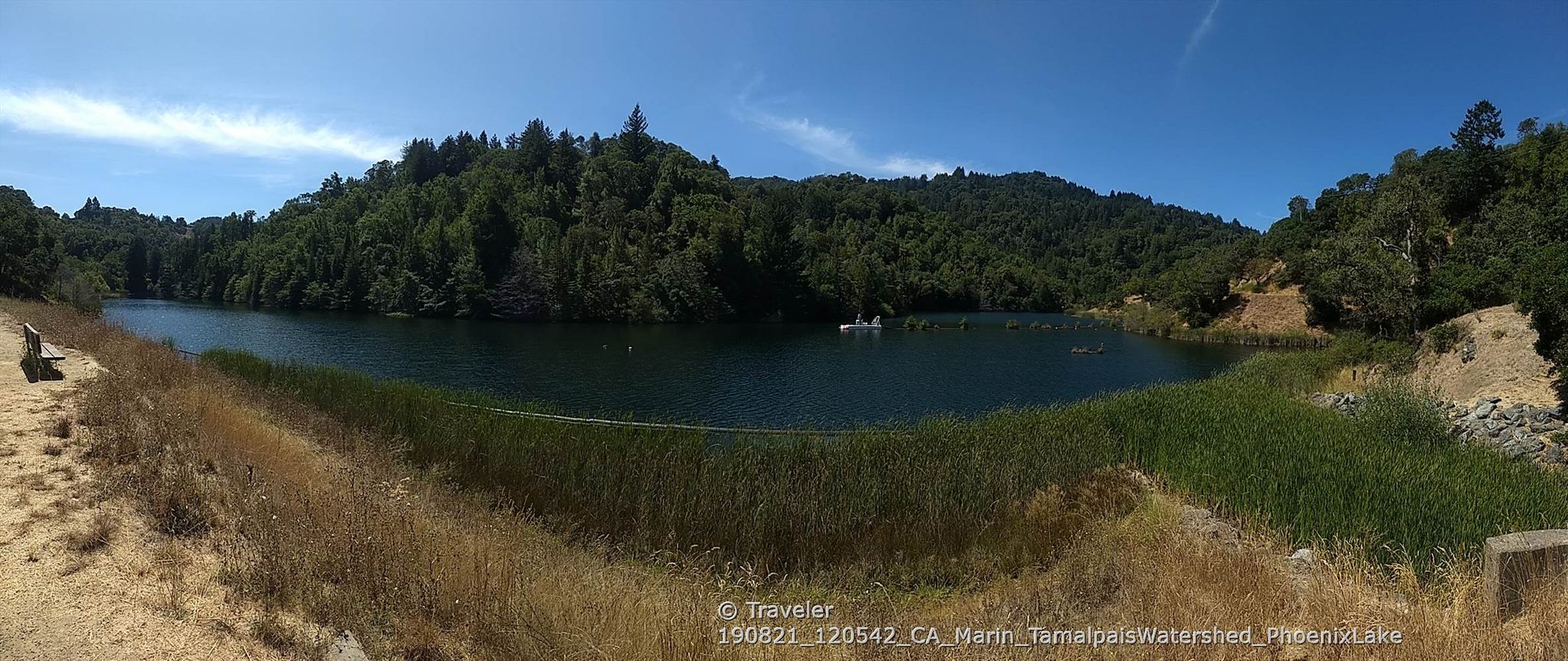Panoramic view of a lake surrounded by green hills under a bright sky. - Phoenix Lake loop
